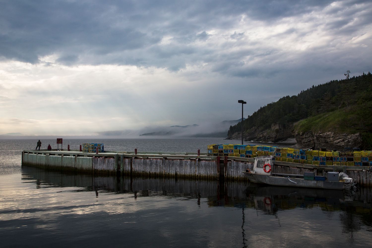 Moody pier with boats at sunset under stormy skies.