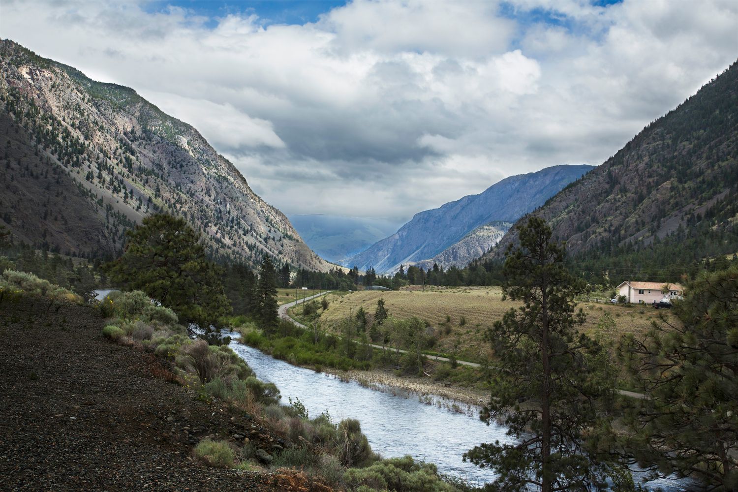Winding river flows through mountain valley with dramatic peaks rising on both sides.
