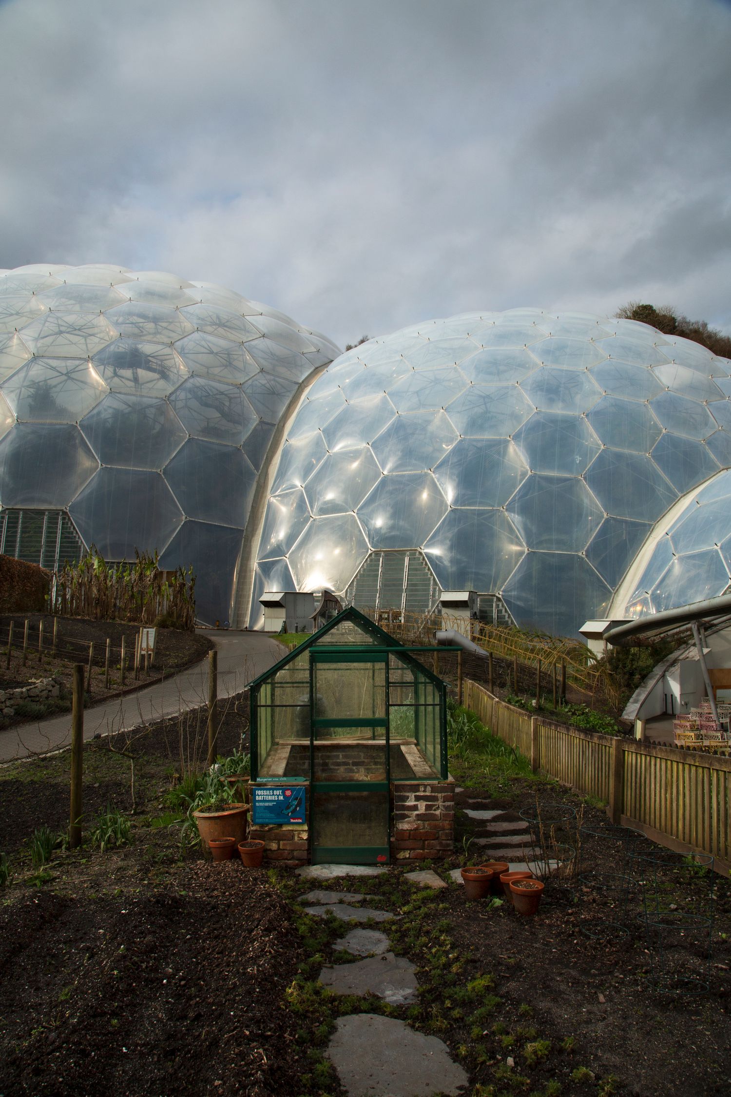 Geodesic domes of the Eden Project with a small greenhouse in the foreground.