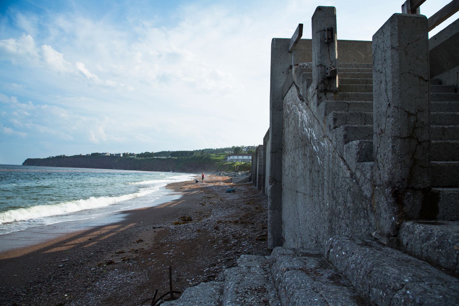 Concrete pier structures frame a dark sandy beach stretching into the distance.
