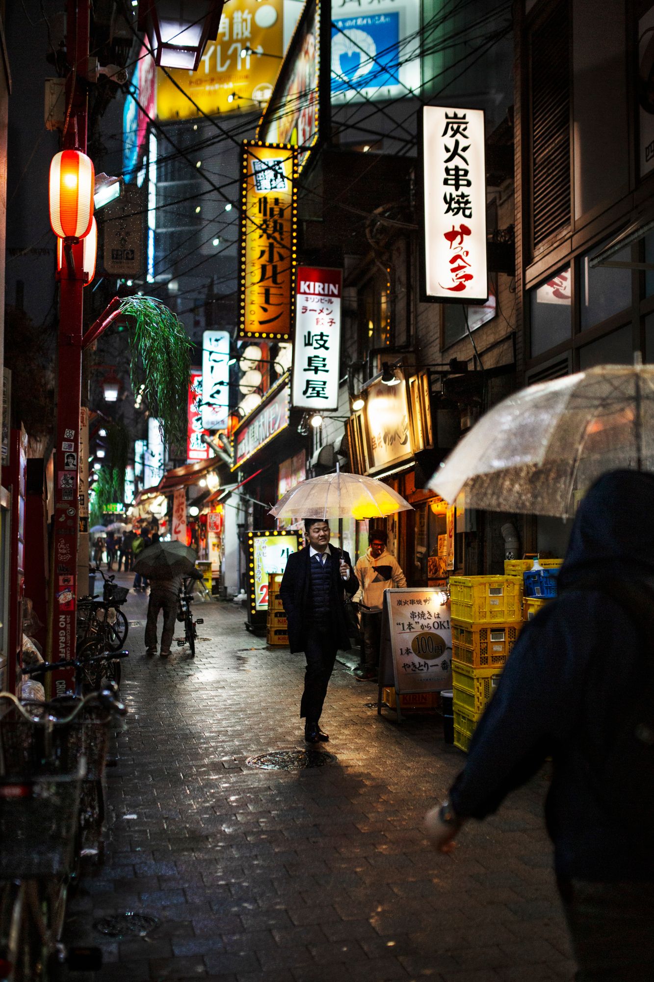 Nighttime street in Japan with colorful neon signs and lanterns illuminating the path.