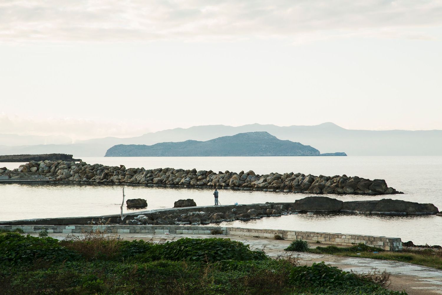 Rocky coastal landscape with distant mountains and rugged shoreline.