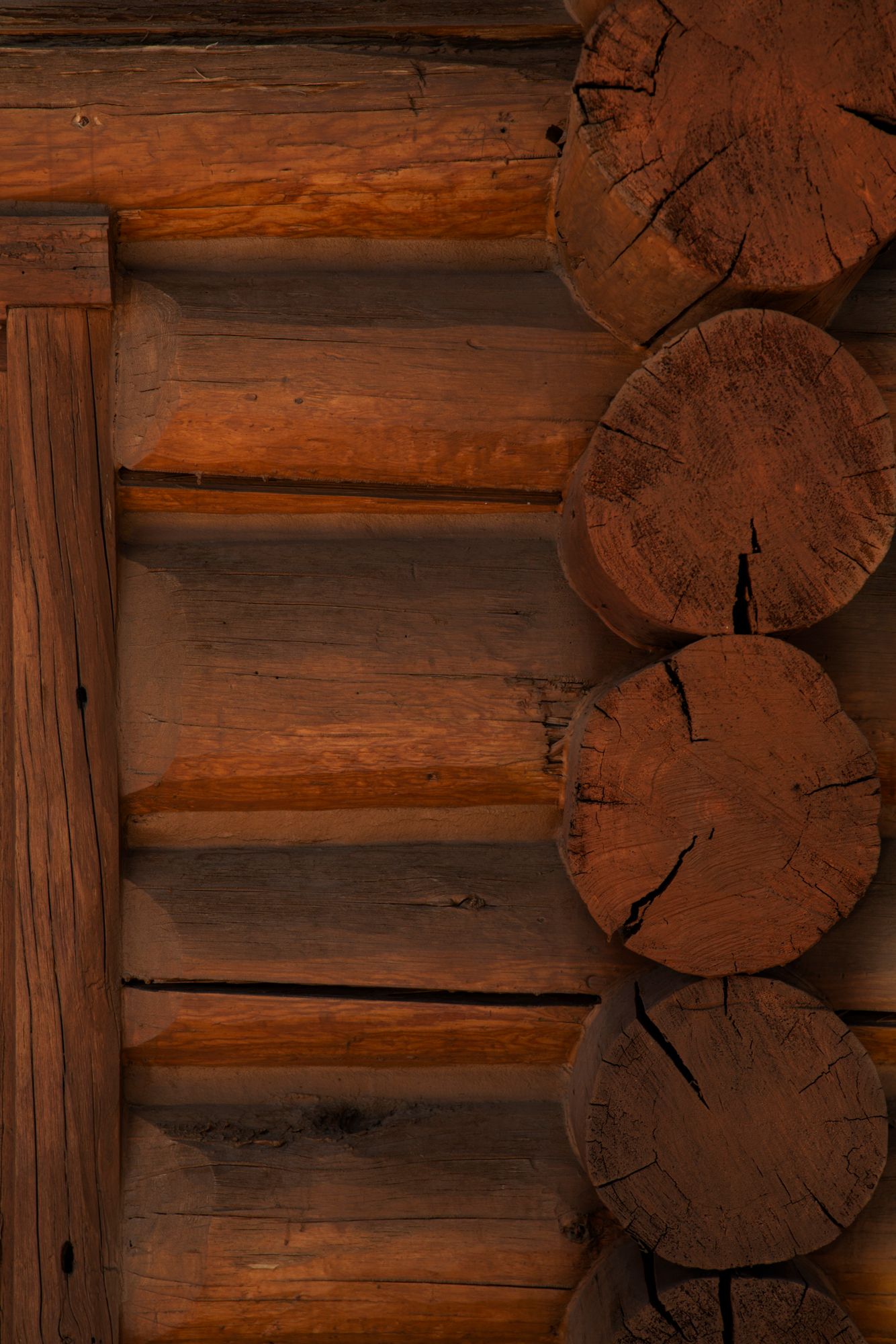 Rustic wooden log cabin wall with interlocking brown timber beams showing natural grain patterns and corner joints.
