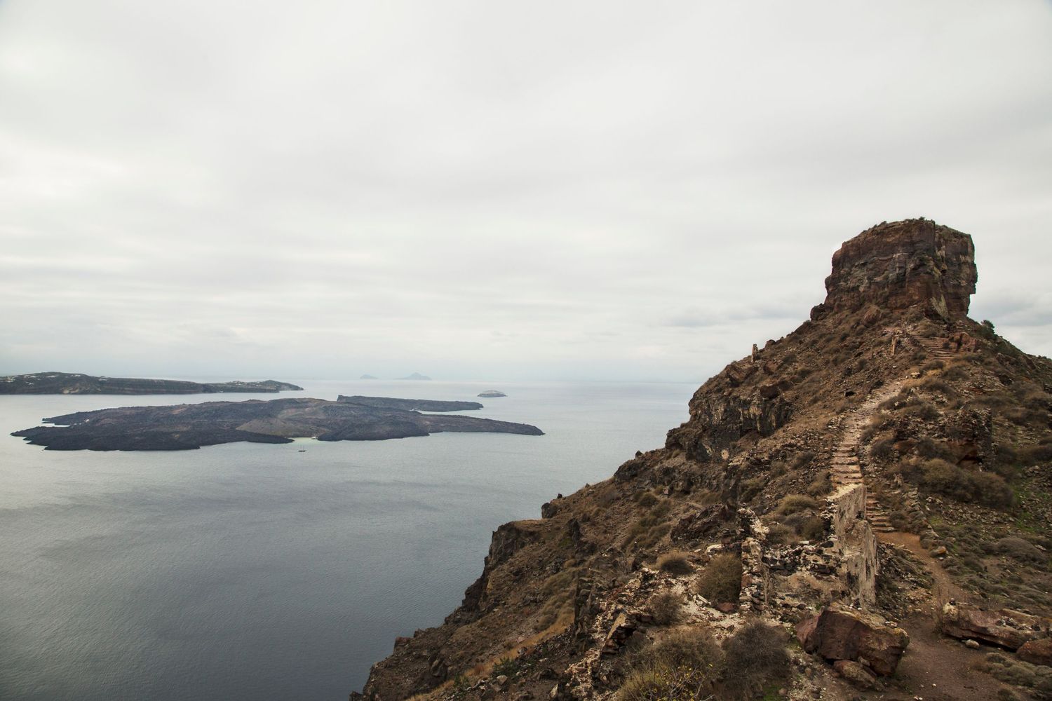 Sweeping coastal landscape showing dramatic cliffs and distant islands in the Aegean Sea.