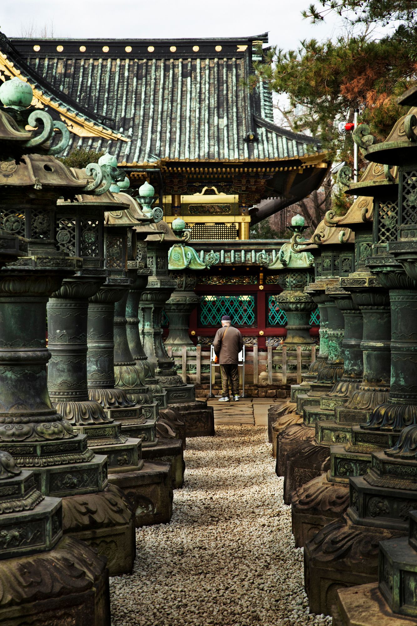Row of traditional Japanese bronze lanterns at a temple courtyard with ornate architectural details.