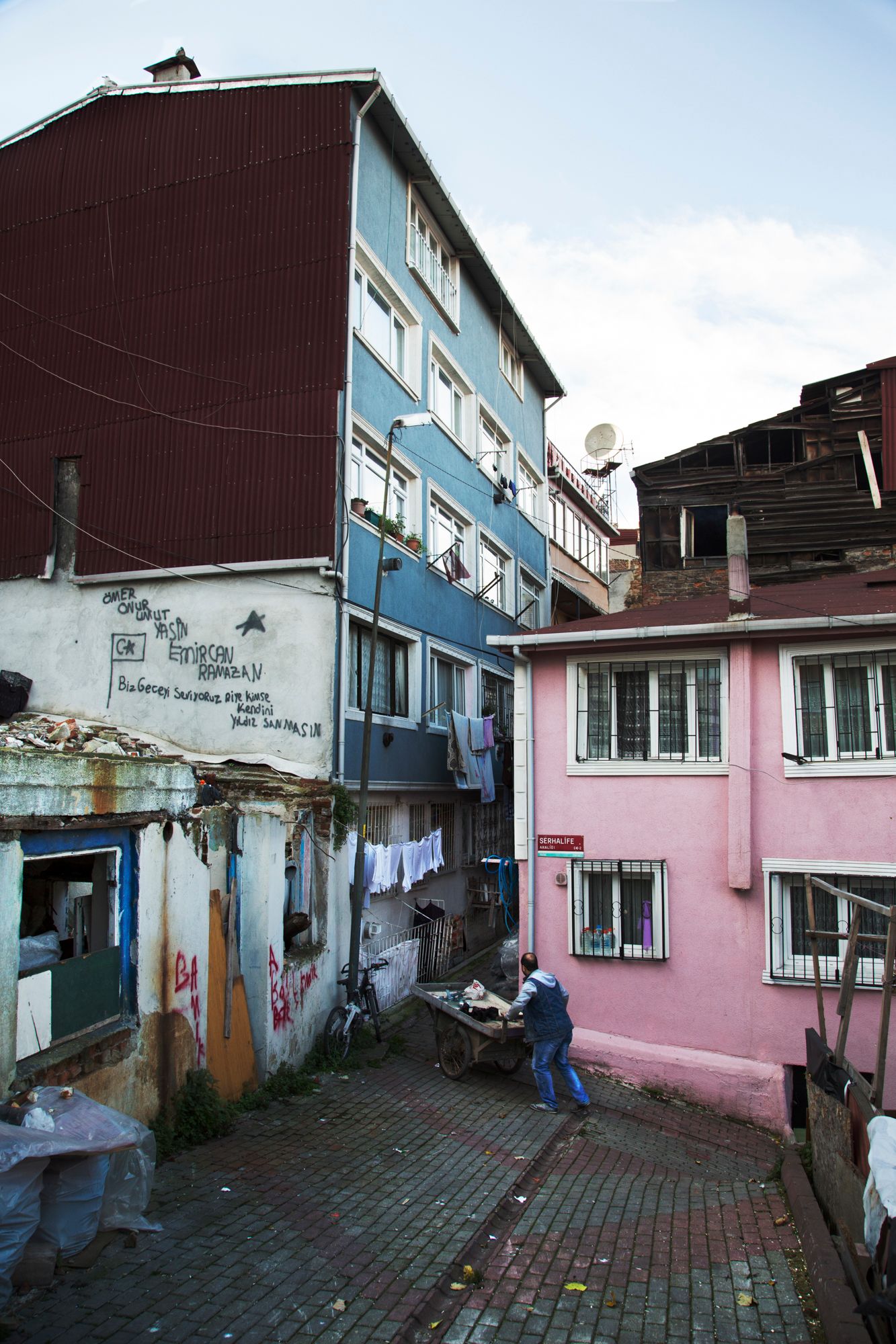Multi-colored apartment buildings with hanging laundry and graffiti in urban neighborhood.