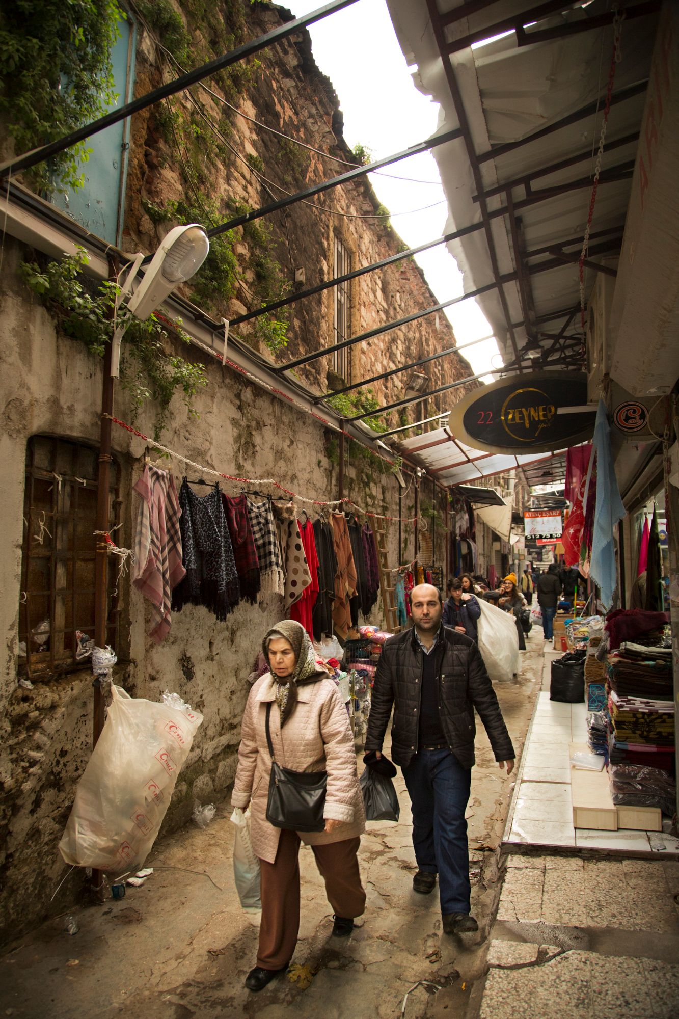 Covered market corridor built into rocky cliffs with vendors displaying goods along the walls.