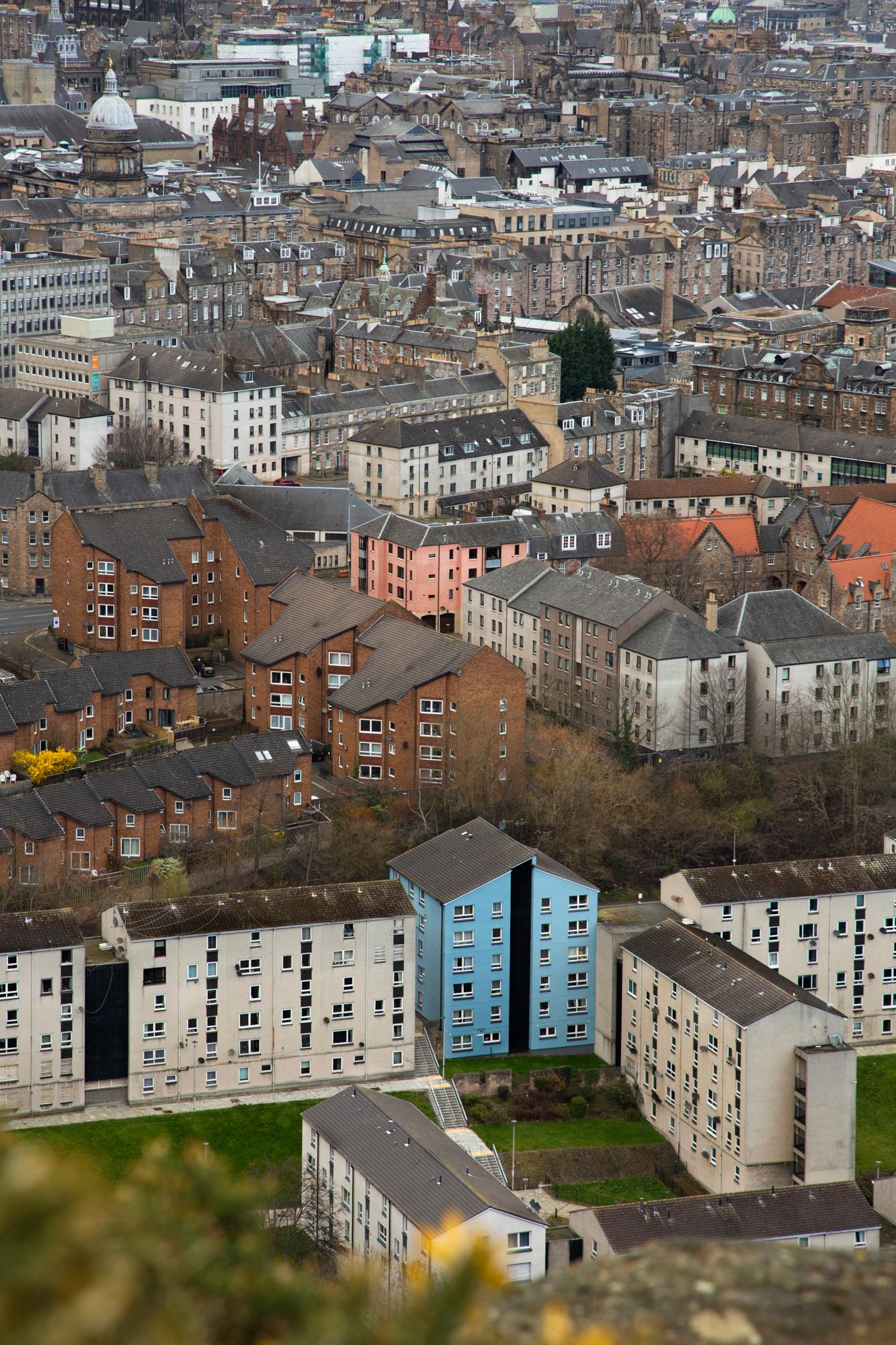 Aerial view of dense urban housing in Edinburgh showing traditional tenement buildings and colorful blue houses.