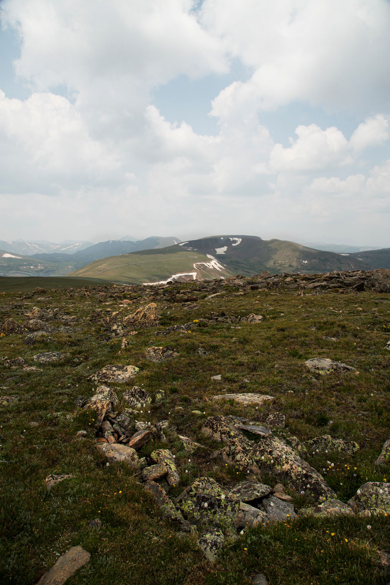 Panoramic view of a rugged mountain landscape with rocky terrain and scattered vegetation under cloudy skies.