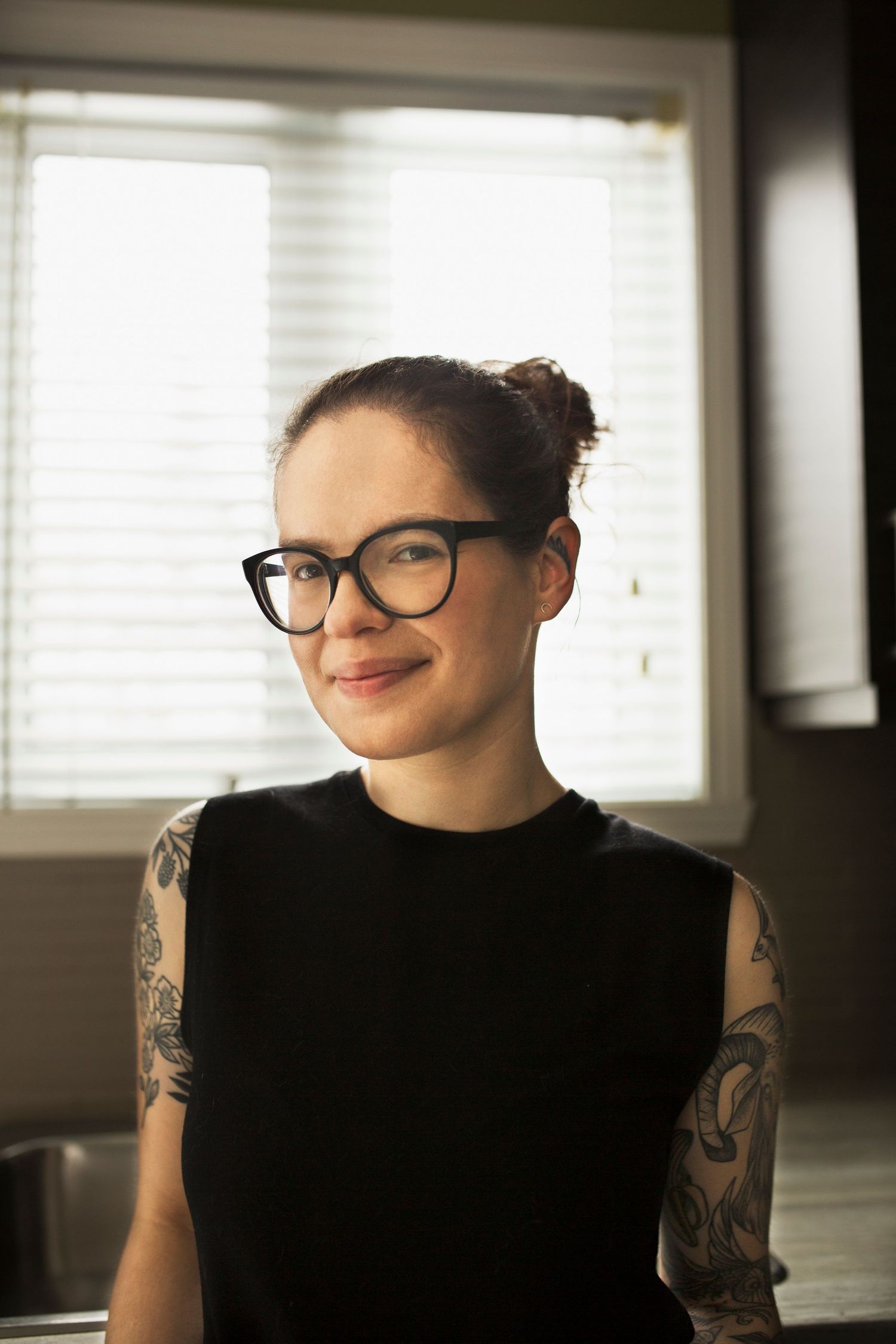 Portrait series in natural window light showing joyful expressions and artistic tattoos.