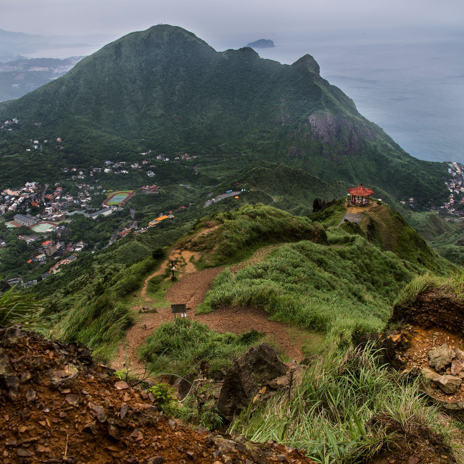 Panoramic view of coastal mountains with settlements nestled on green hillsides.