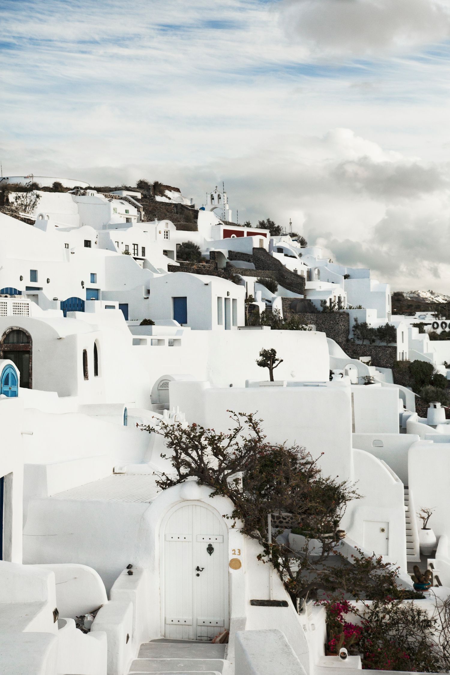 Traditional white Greek village buildings cascading down hillside with blue accents.