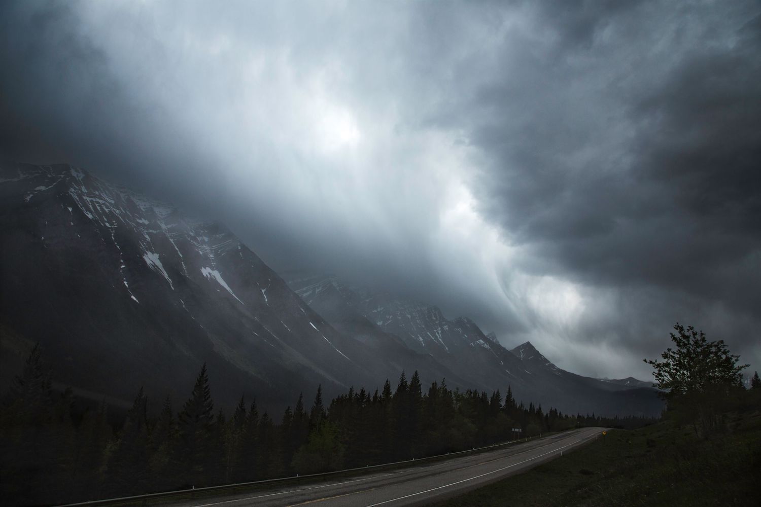 Storm clouds gathering over dark mountain silhouettes in a moody landscape.