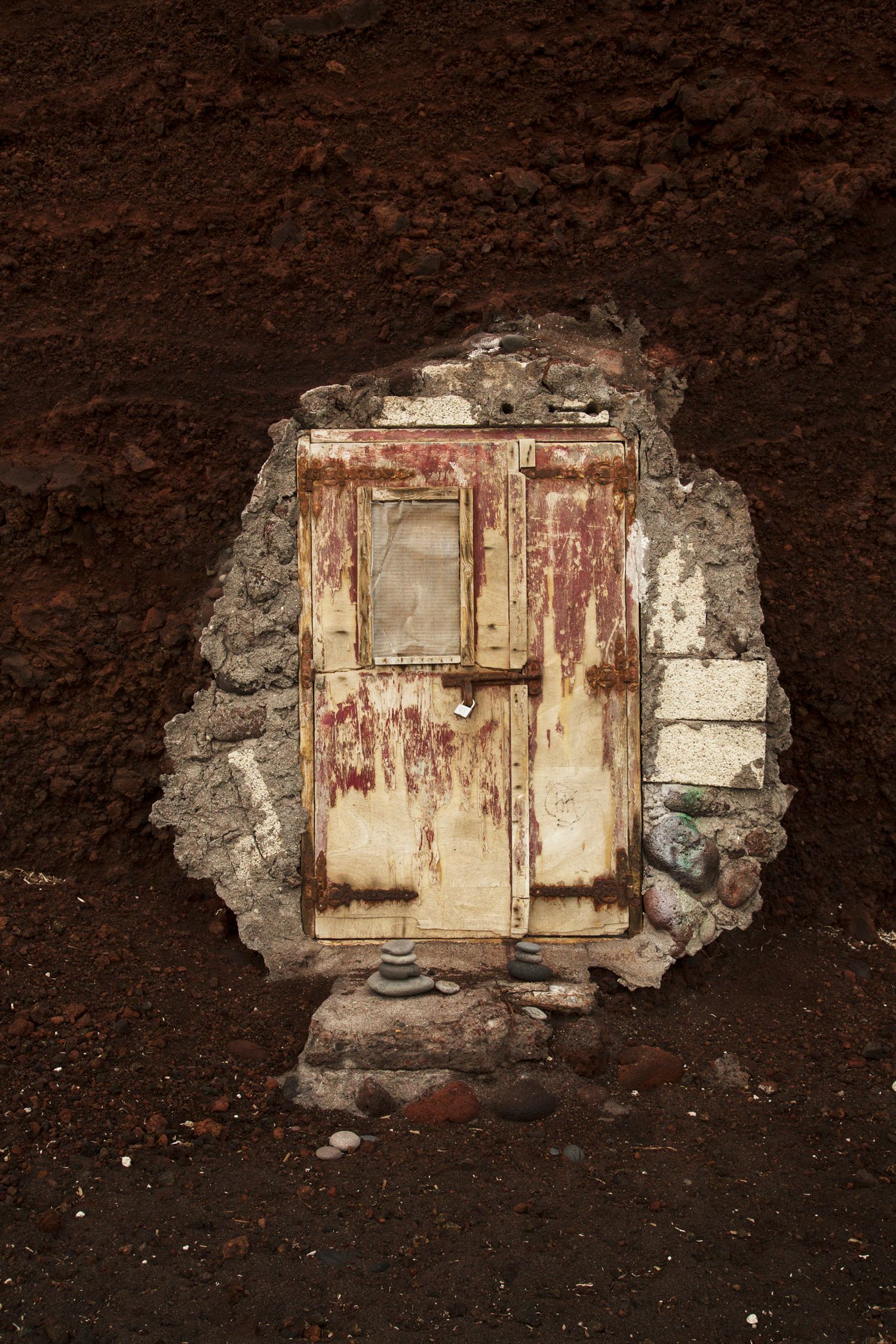 Weathered wooden door set in crumbling stone wall reveals dark earthen background.