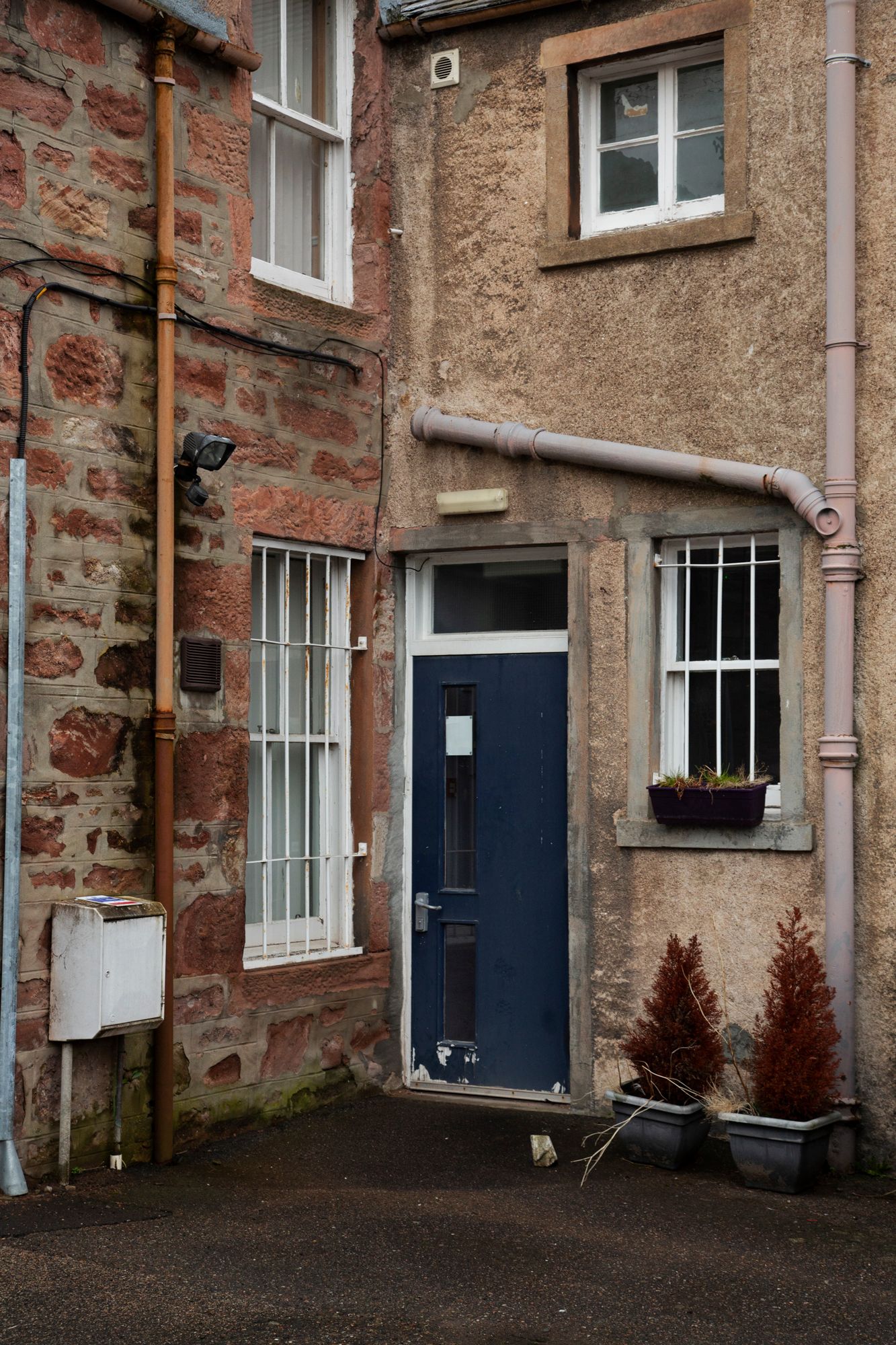 Exterior view of traditional stone building with blue doors and windows showing architectural details in Scotland.