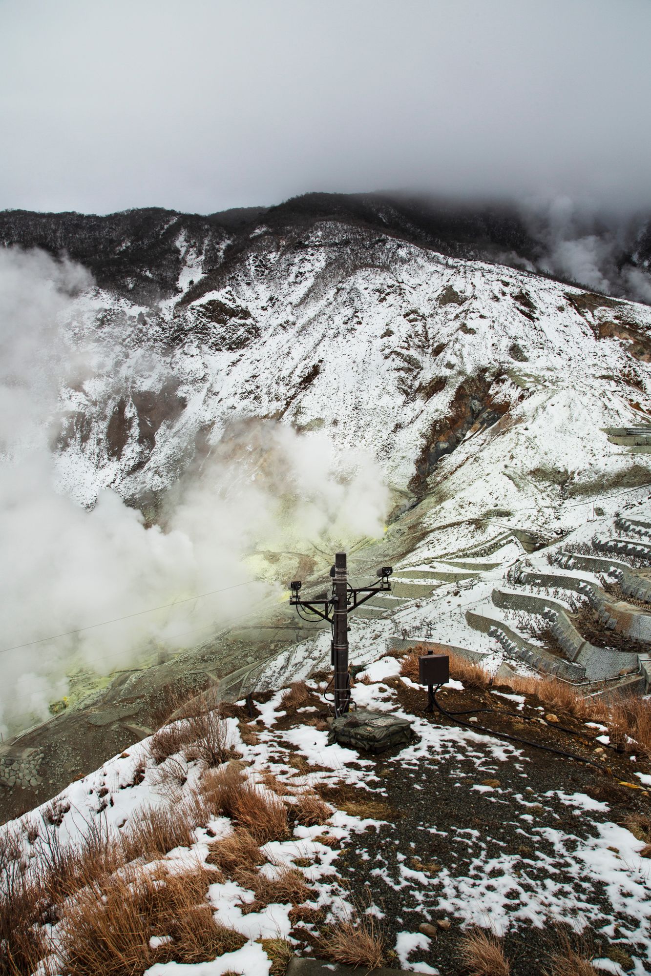 Snow-covered volcanic landscape with steam rising from hot springs in Japan.