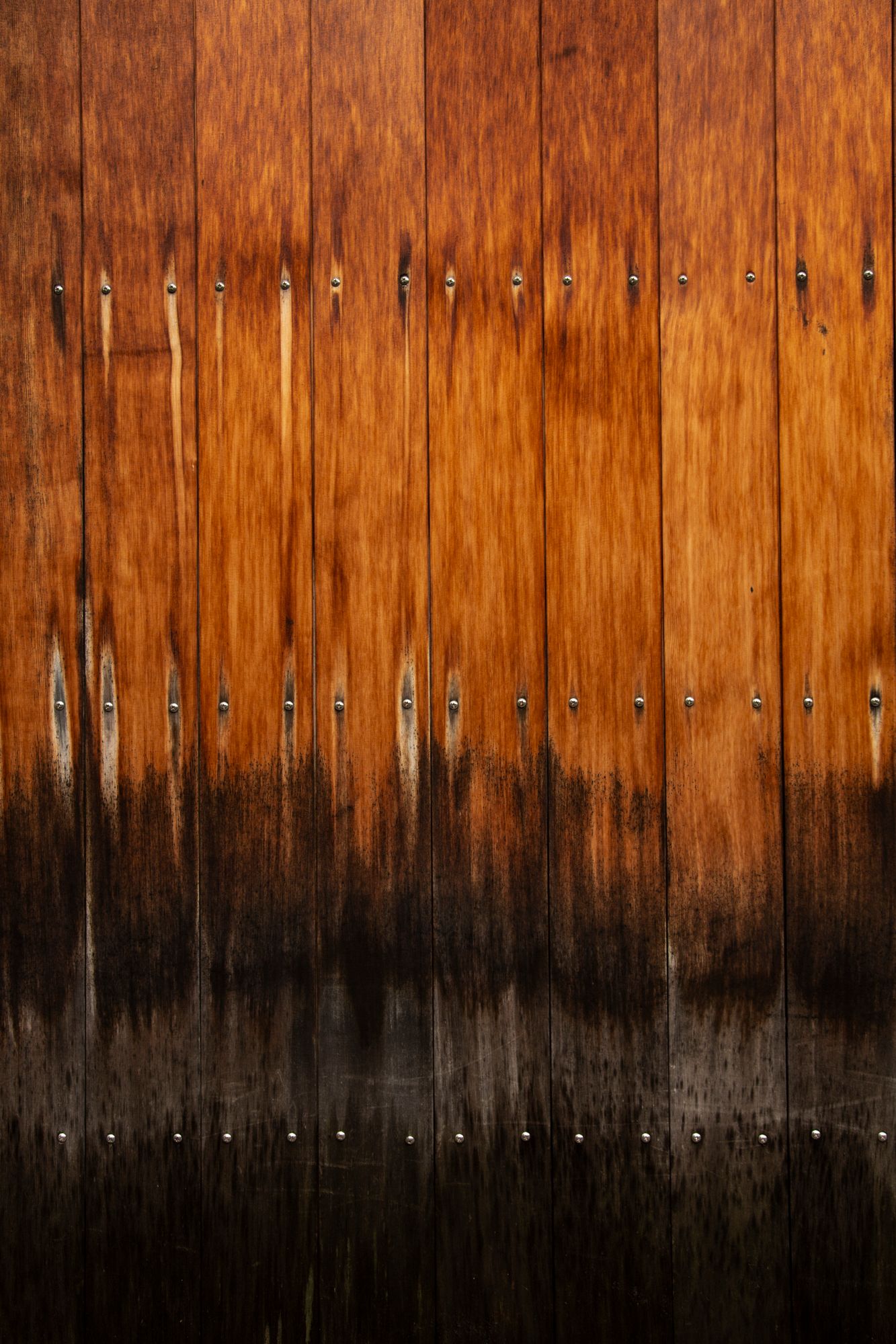 Weathered wooden wall panels with vertical grain pattern and dark bottom edge.