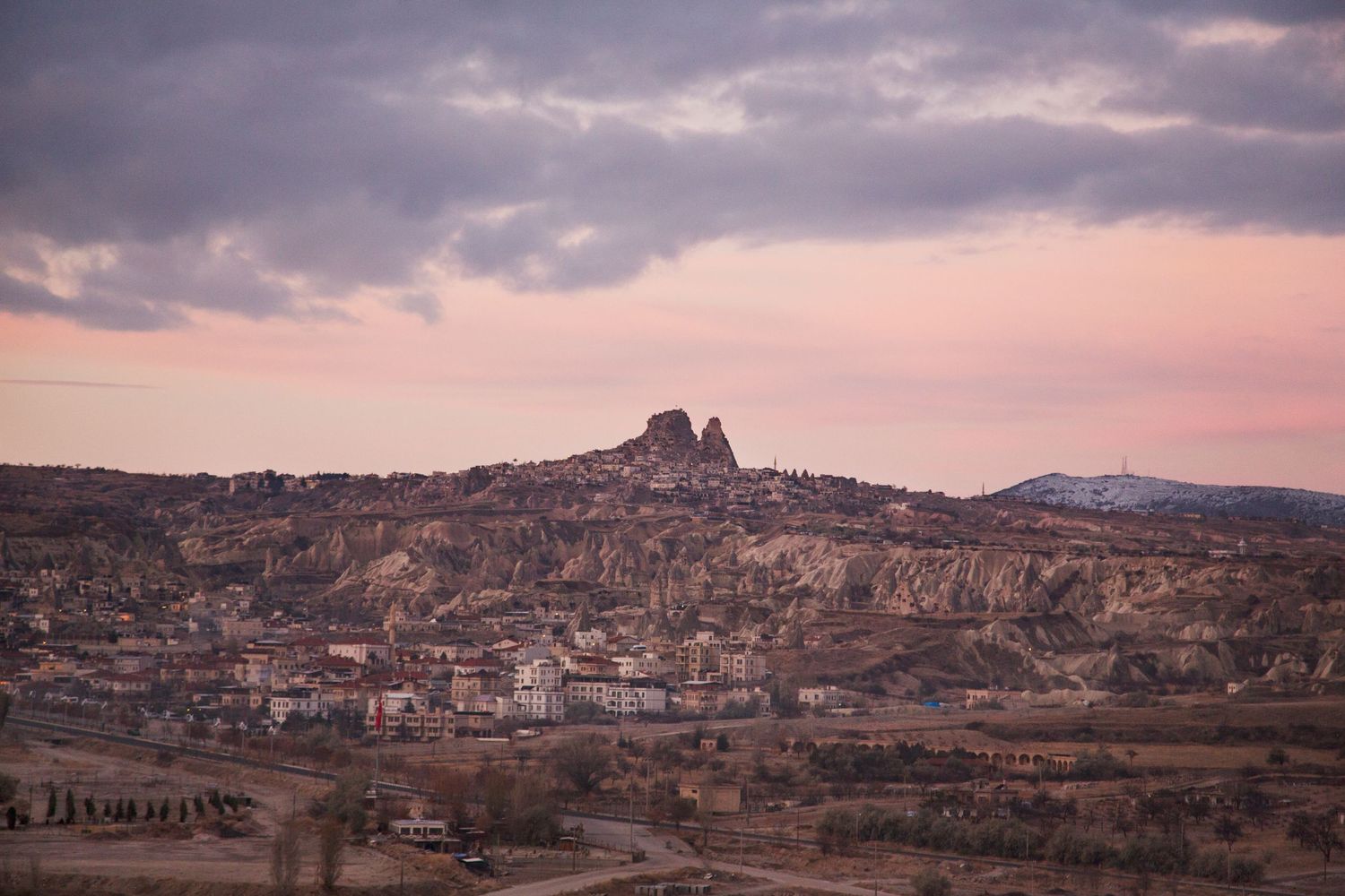 Panoramic sunset view of a Mediterranean city sprawling across hilly terrain.