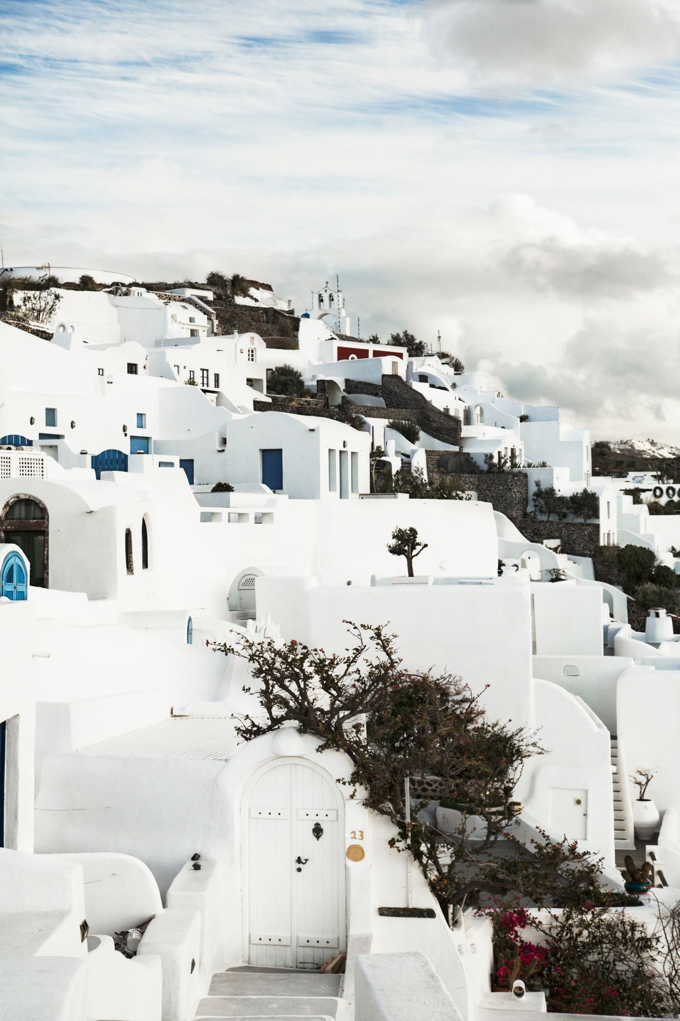 White-washed buildings cascading down hillside in Santorini, Greece.