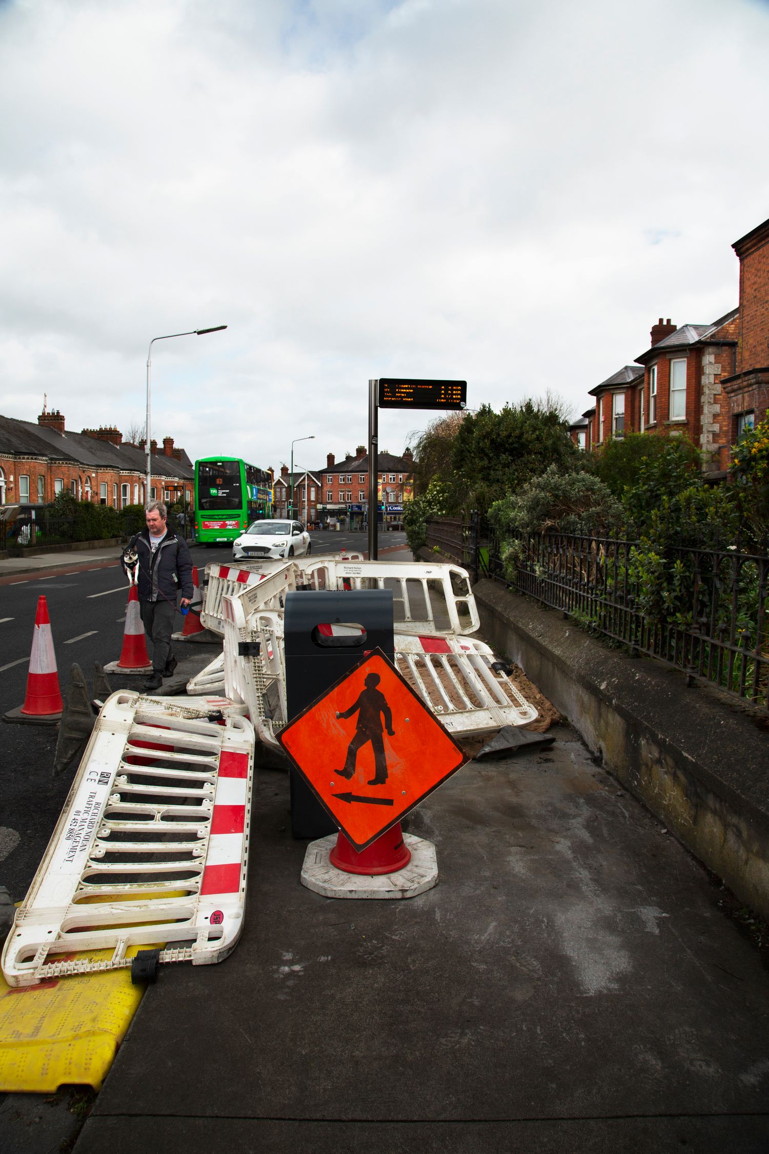 Construction barriers and warning signs laid out on dark asphalt street.