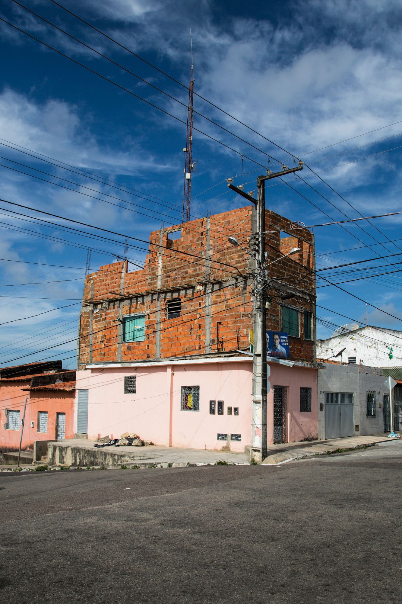 Colorful residential street with exposed brick buildings and power lines under bright blue sky.
