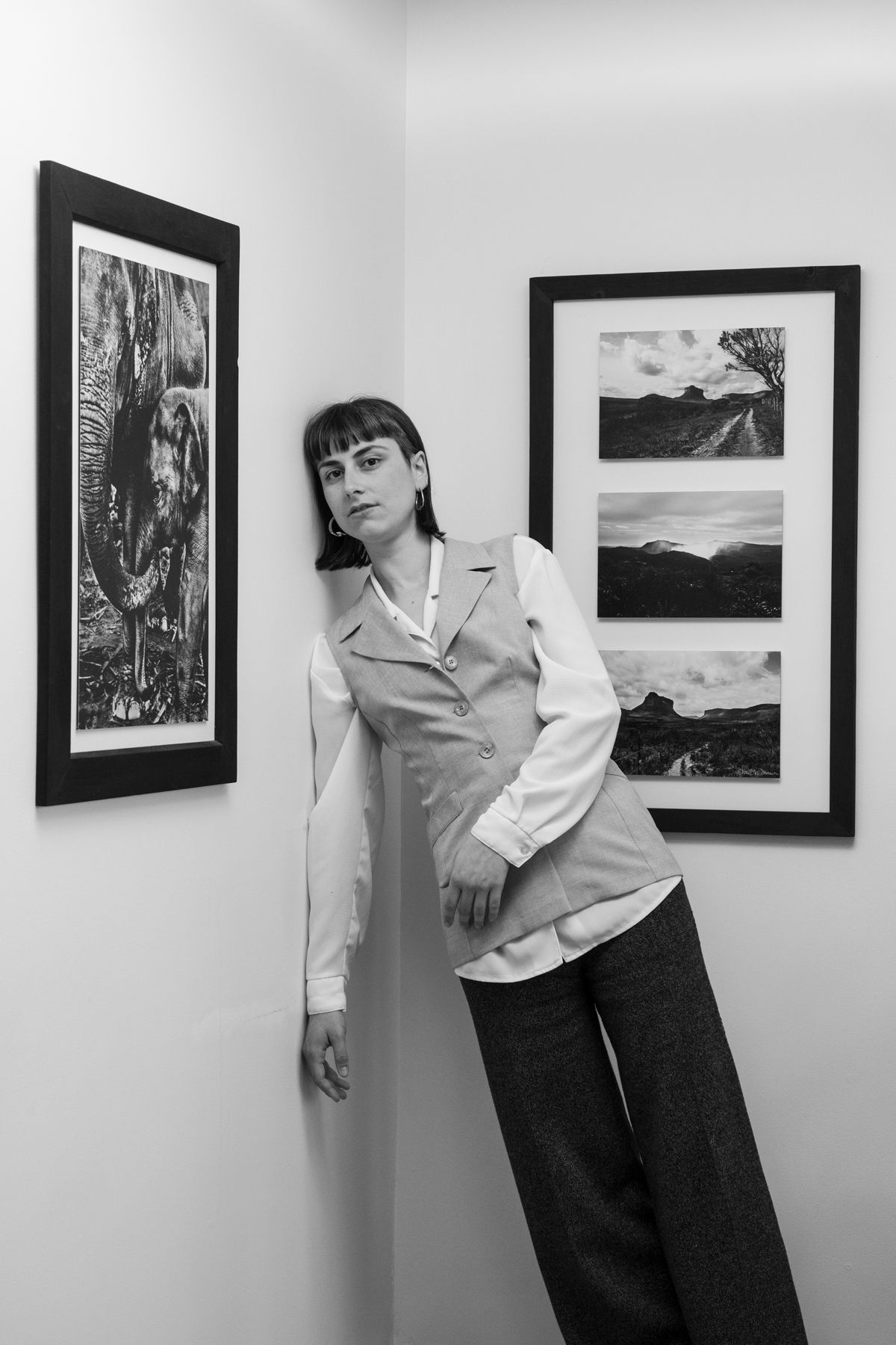 An artistic black and white portrait taken in a gallery space with framed photographs.