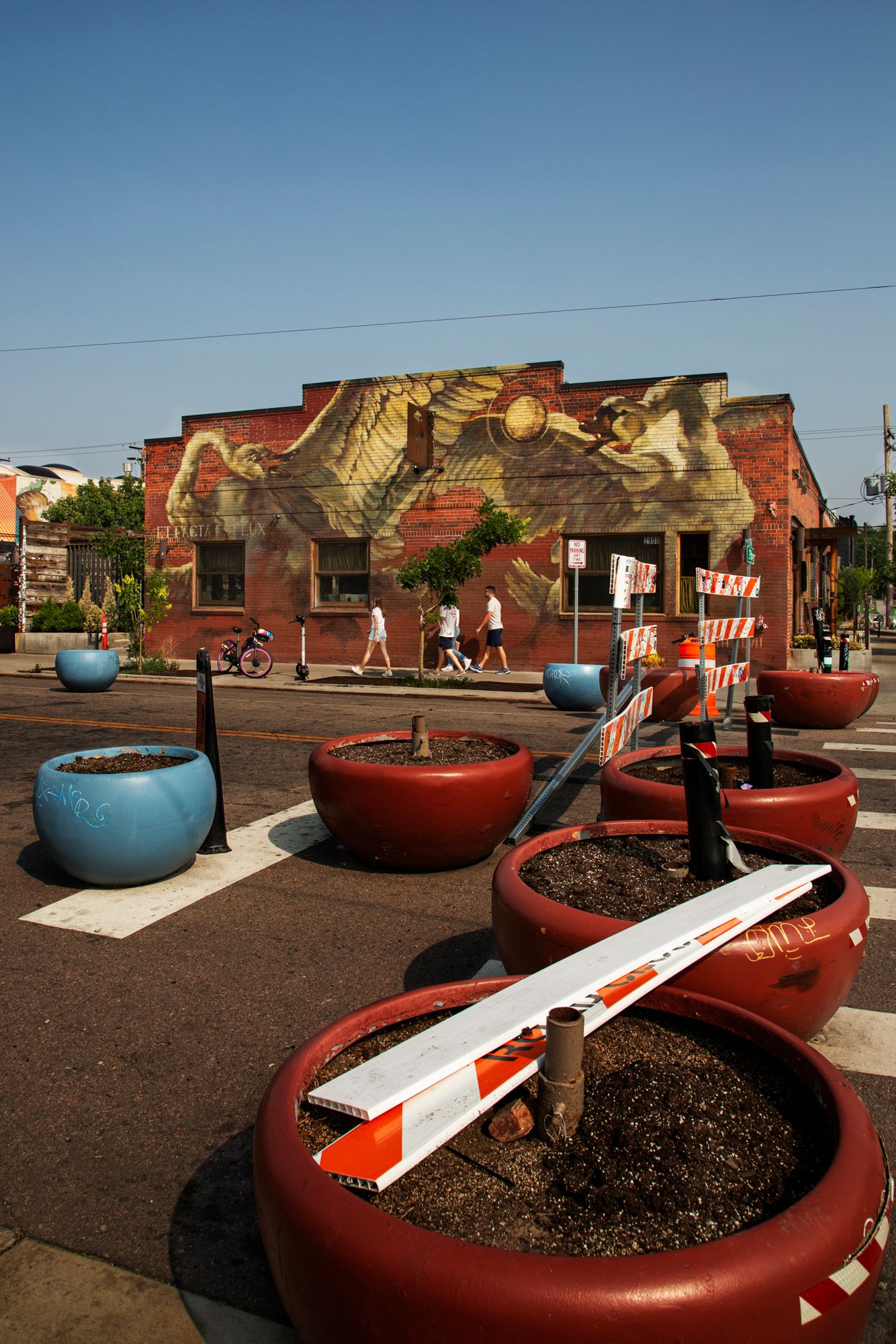 Curved red and blue planter benches with desert landscaping arranged in front of a painted mural wall.