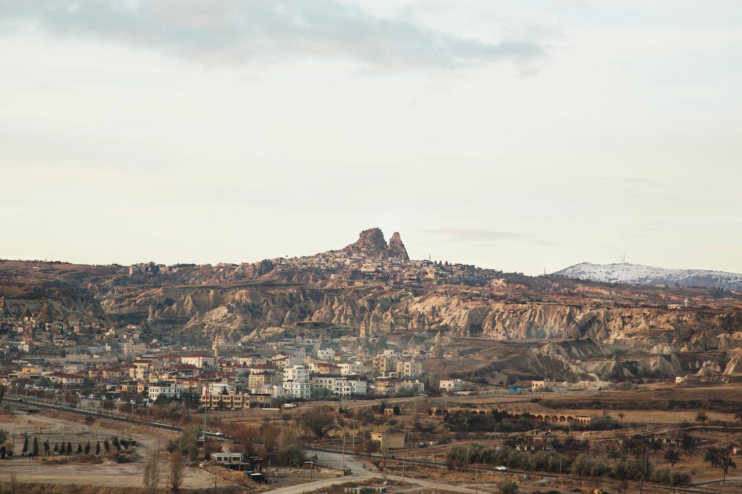 Panoramic view of Cappadocia's rocky landscape and settlements during golden hour.