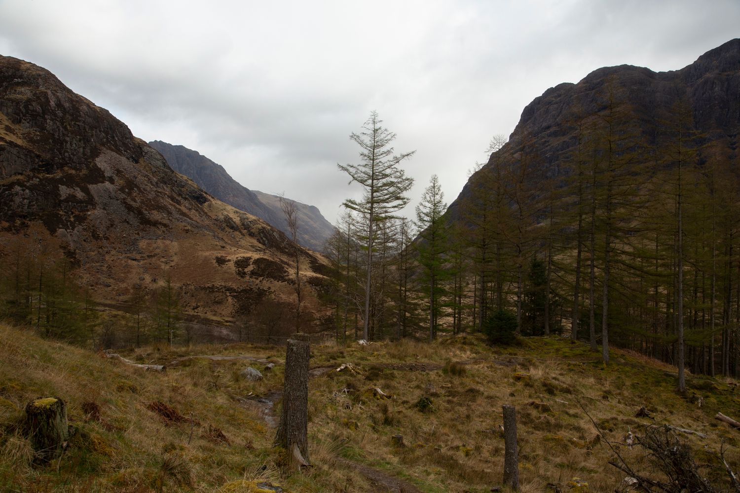 Scenic mountain landscape in Scotland's Glen Coe valley with rugged peaks and dramatic cloudy skies.