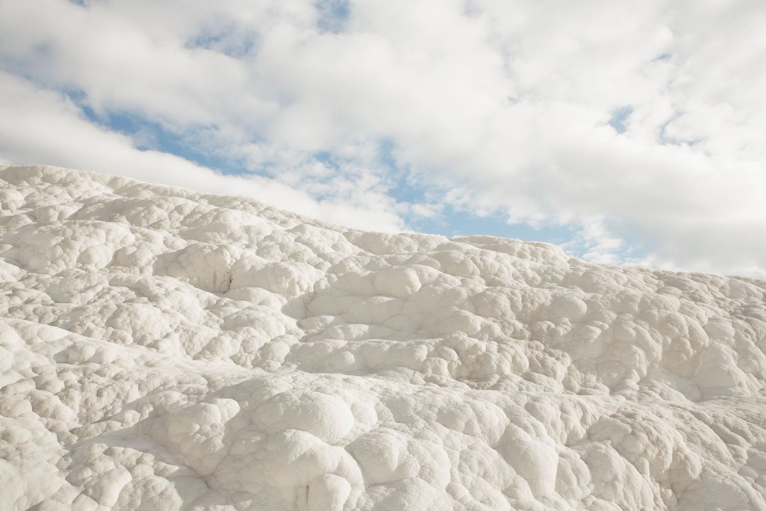 Snow-covered mountain peaks extend across the horizon under a partly cloudy sky.