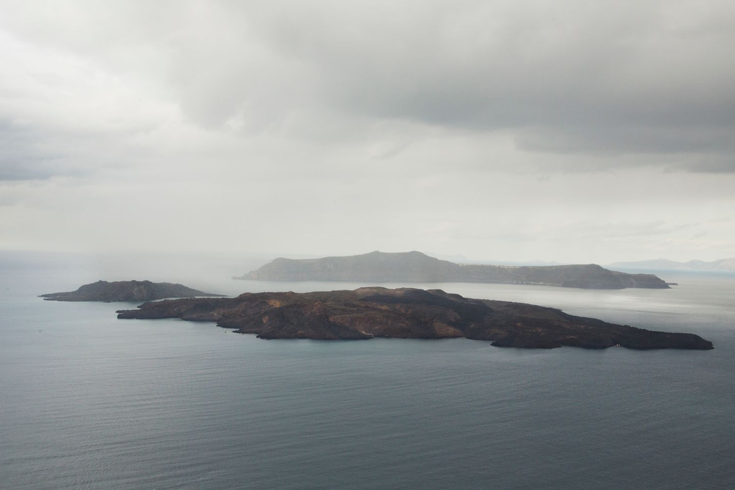 Distant islands emerge from misty waters under overcast skies creating a serene seascape.