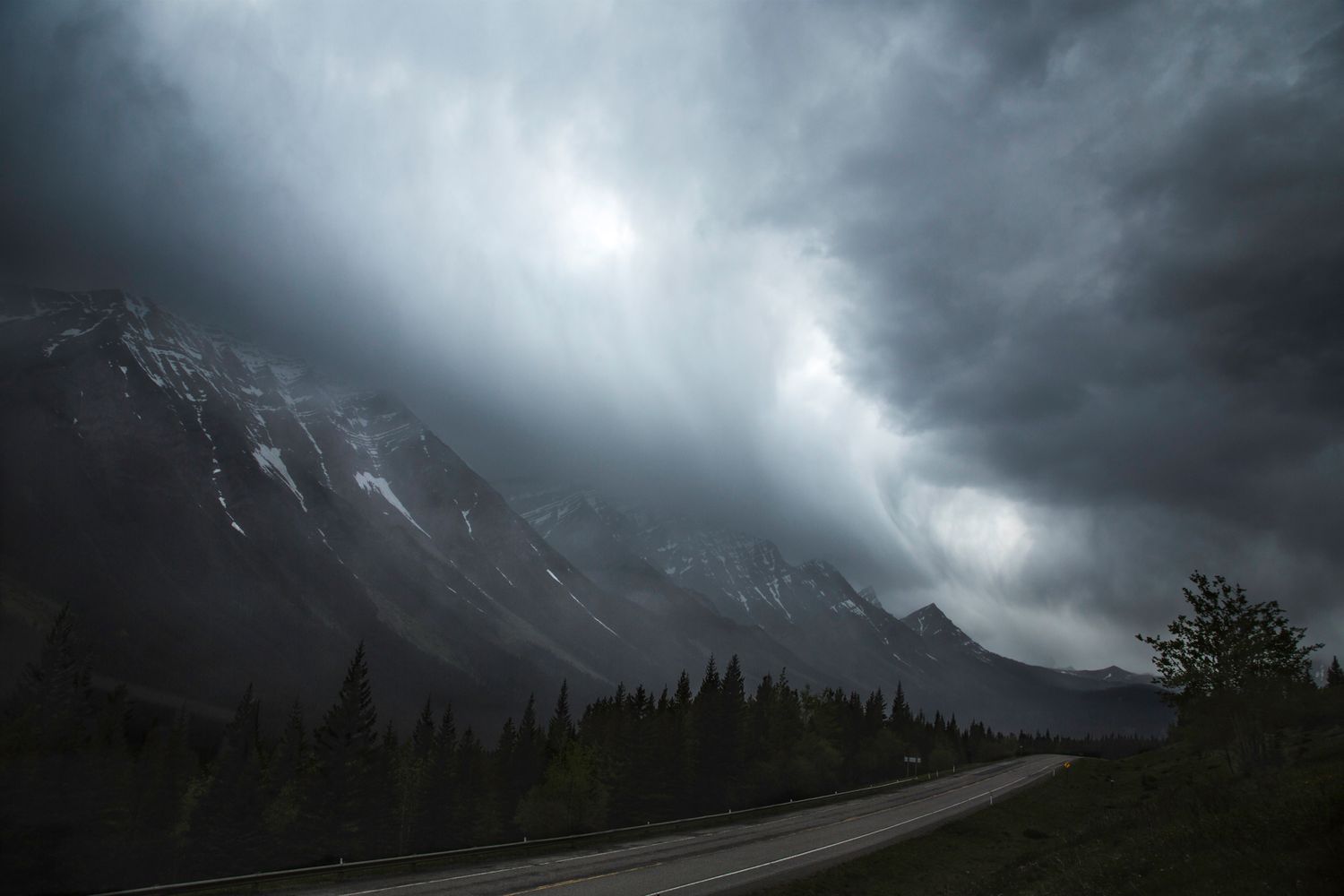 Storm clouds roll over mountain peaks creating moody atmosphere in wilderness landscape.