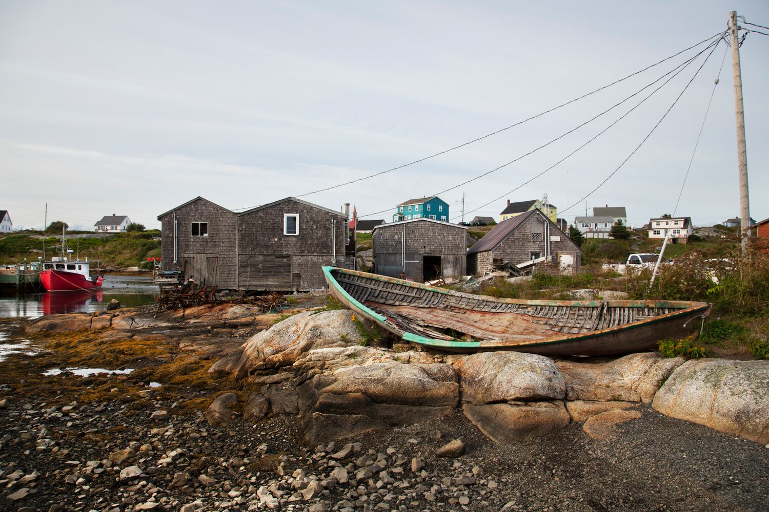 Small fishing village with weathered buildings and boats perched on rocky maritime coast.