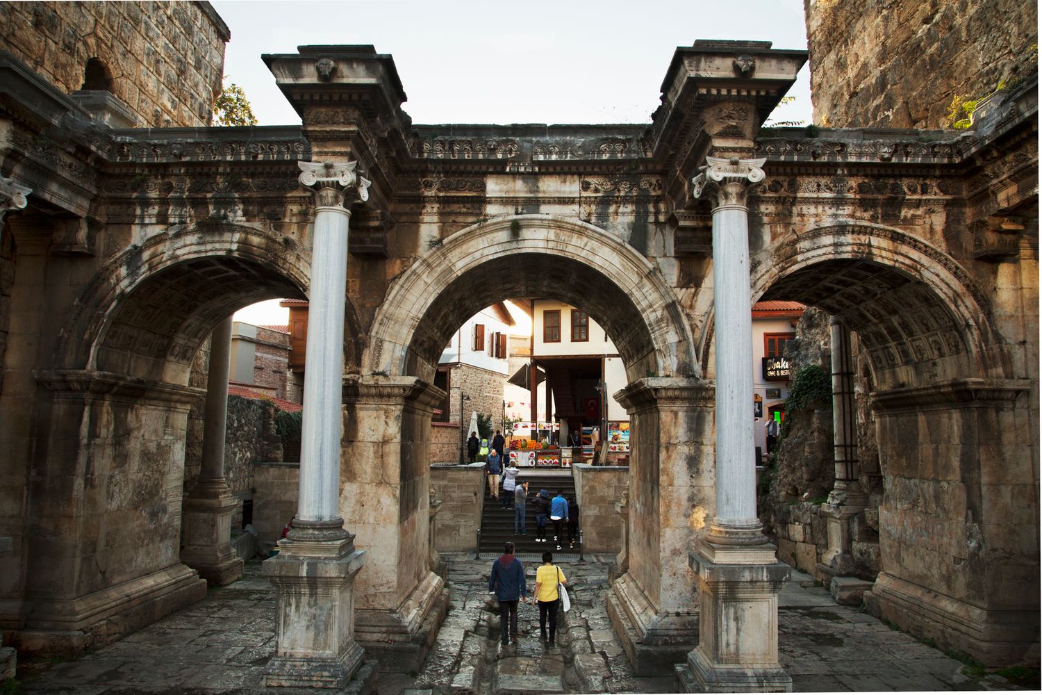 Ancient stone archways and columns in historic European architecture create dramatic corridor.