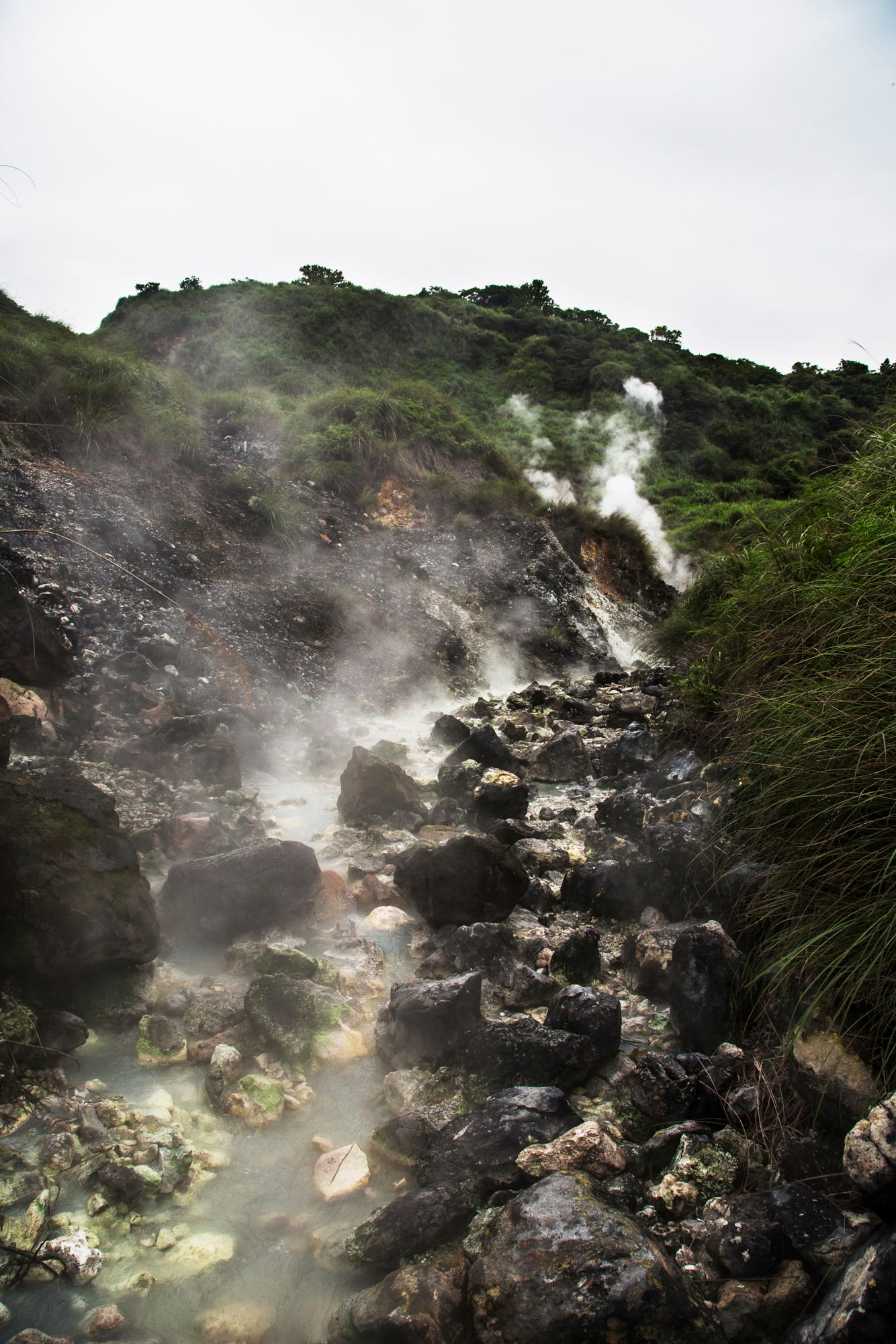 Misty volcanic landscape with steam rising from rocky geothermal vents.