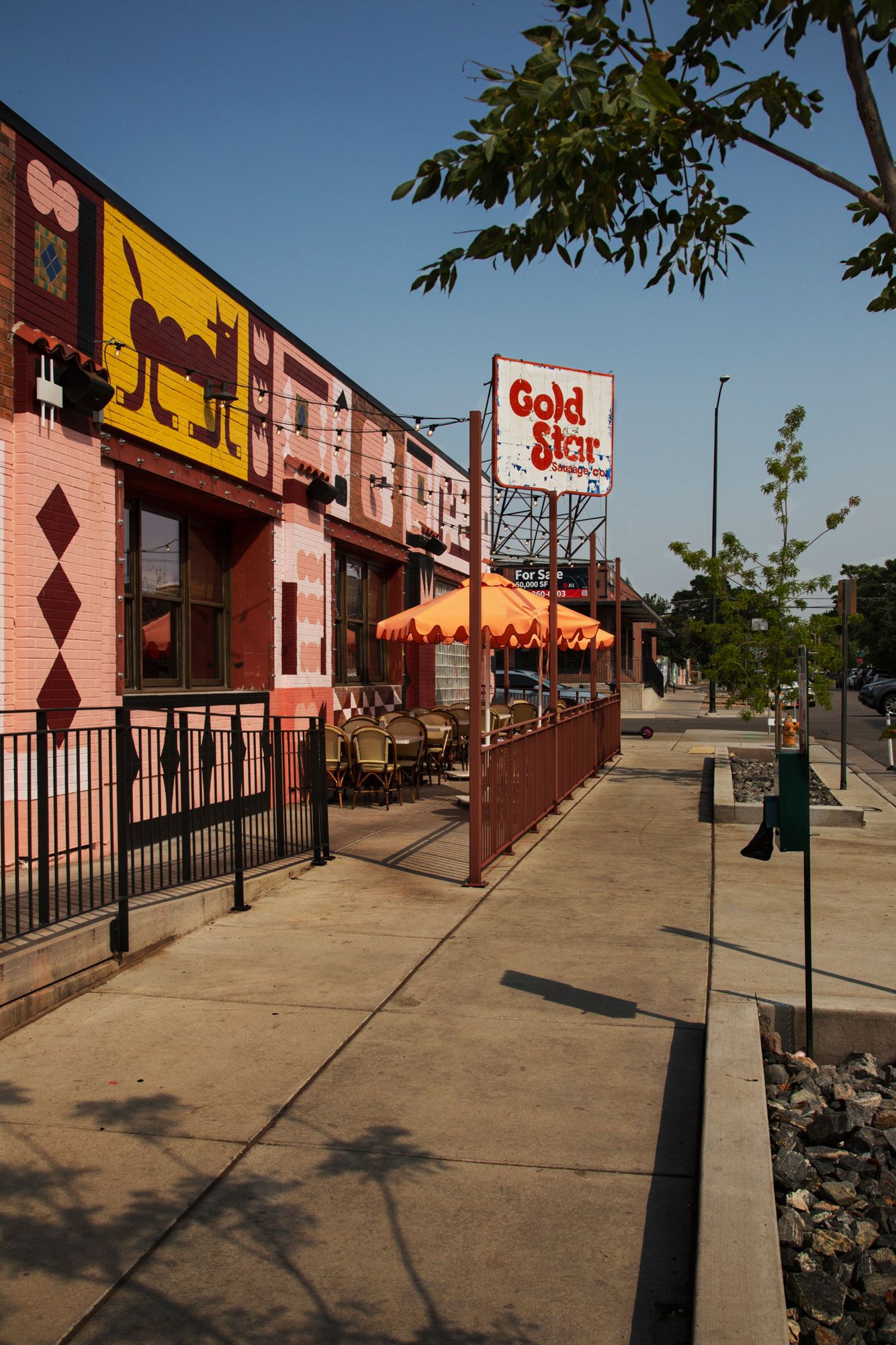 Exterior view of a commercial strip mall with Star and Gold signage along a sidewalk on a sunny day.