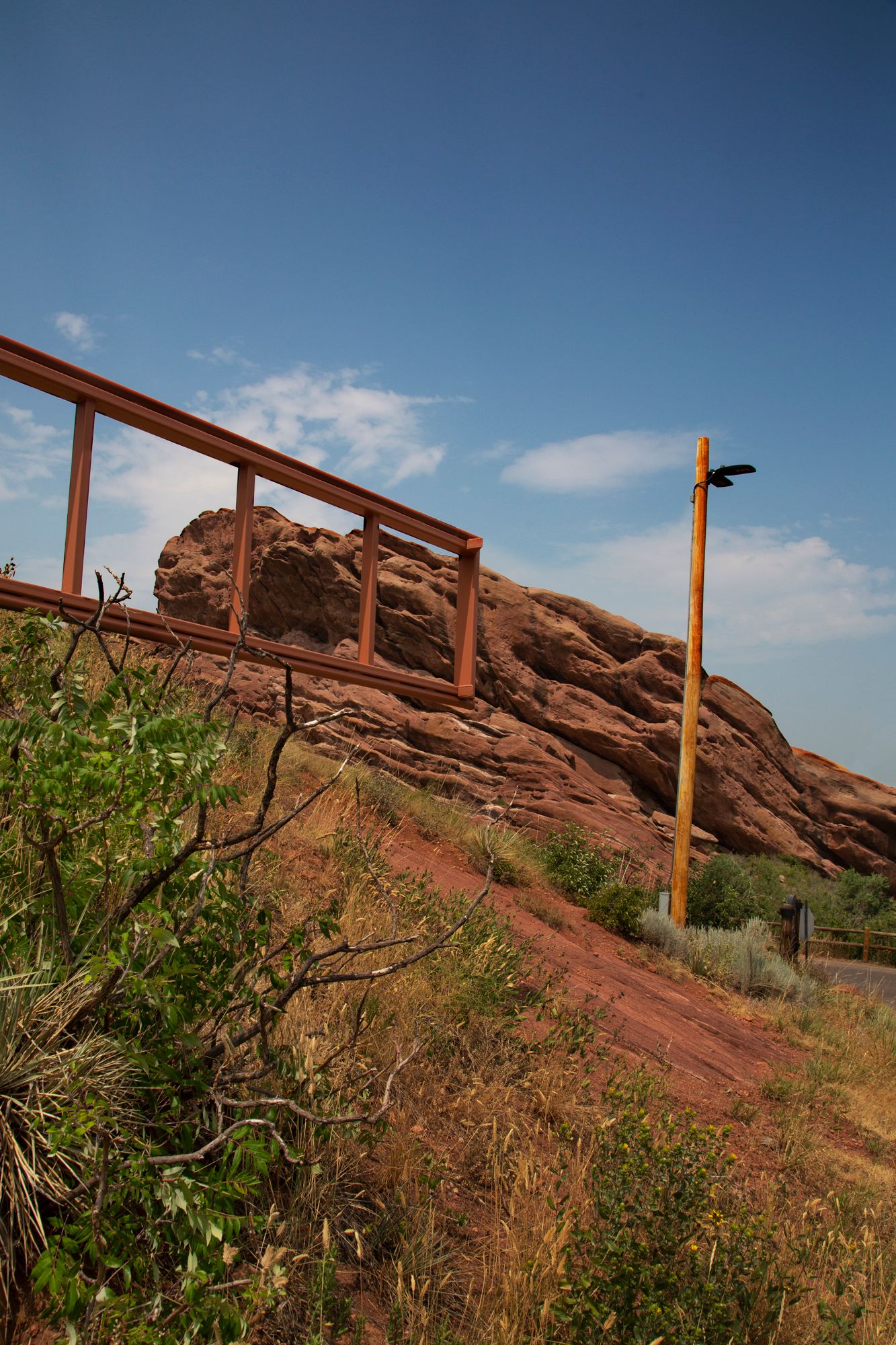 Red rock formations with metal poles and desert vegetation against clear blue sky.