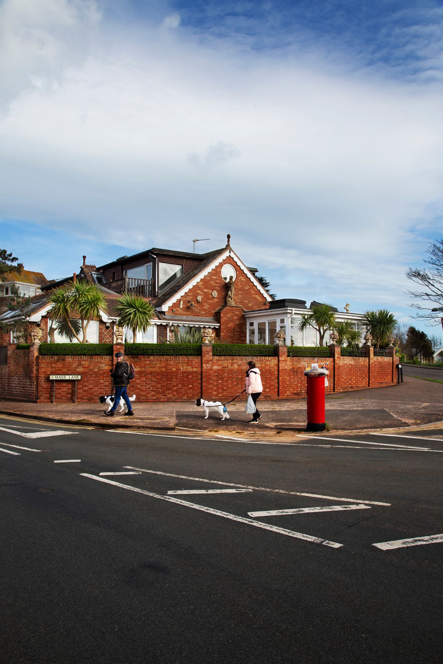 A suburban street corner with red brick walls, traditional houses and a classic British red postbox.