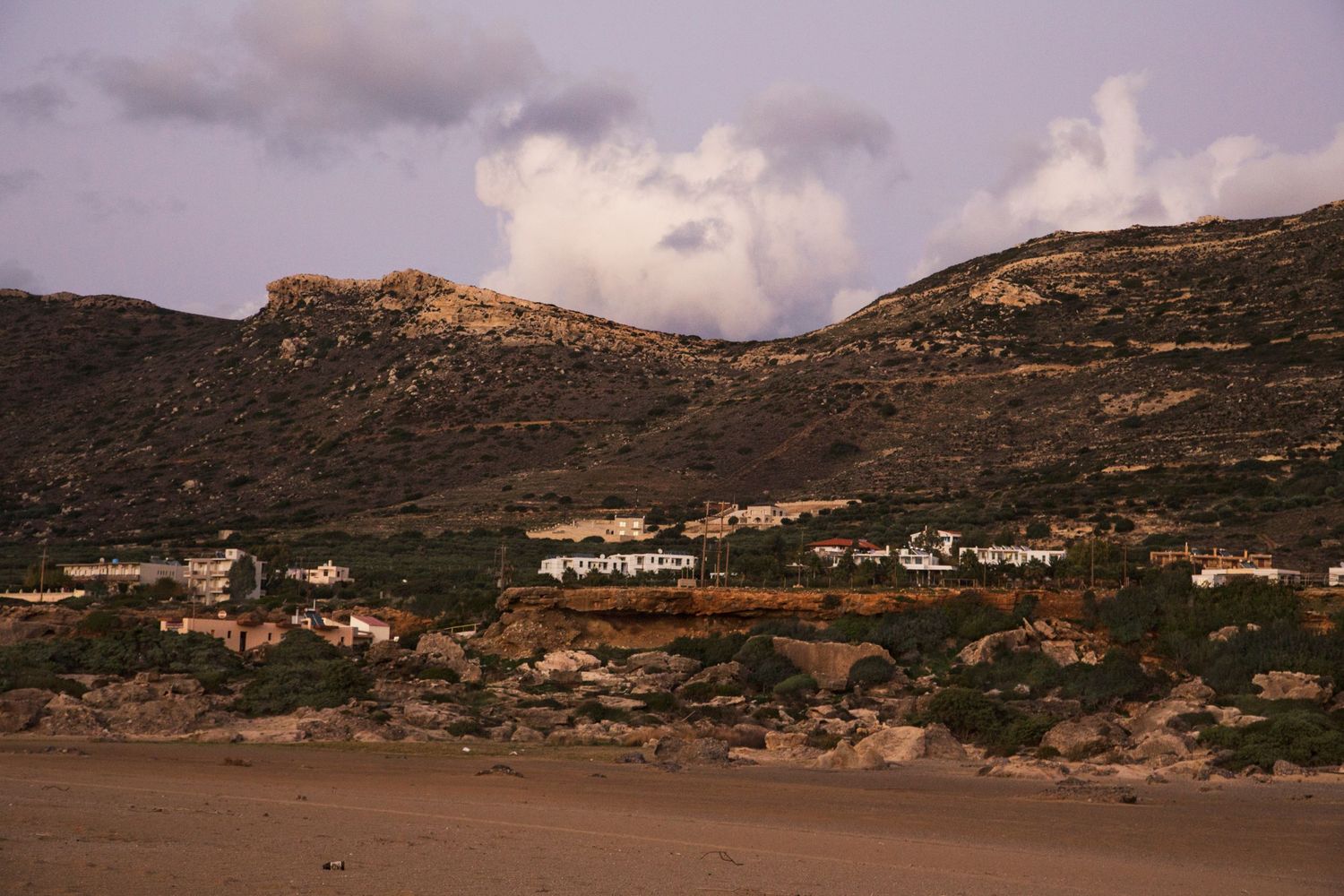 Desert mountain landscape with scattered buildings along arid terrain.