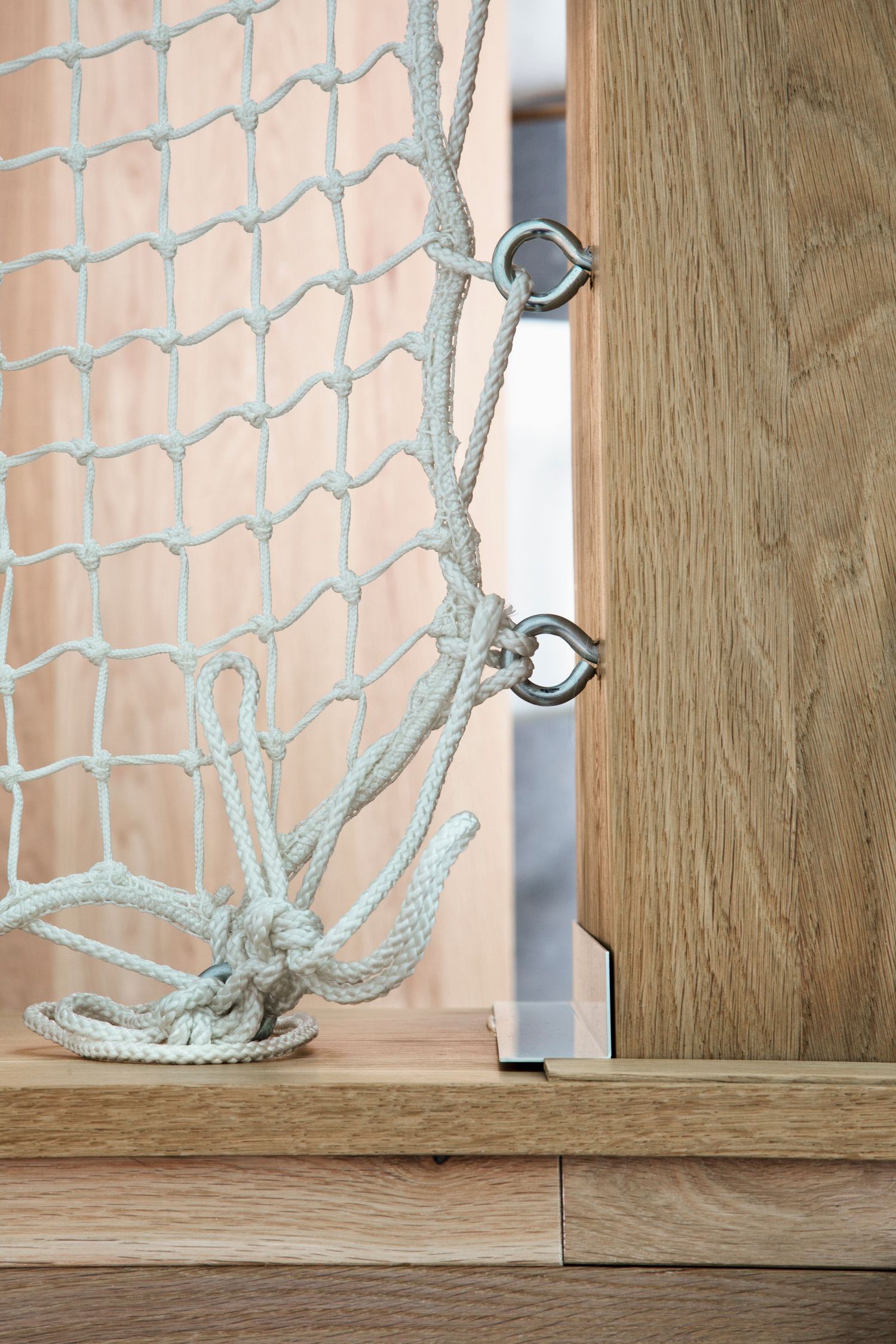 Close-up details of rope or cable mounting hardware against a wooden wall surface.