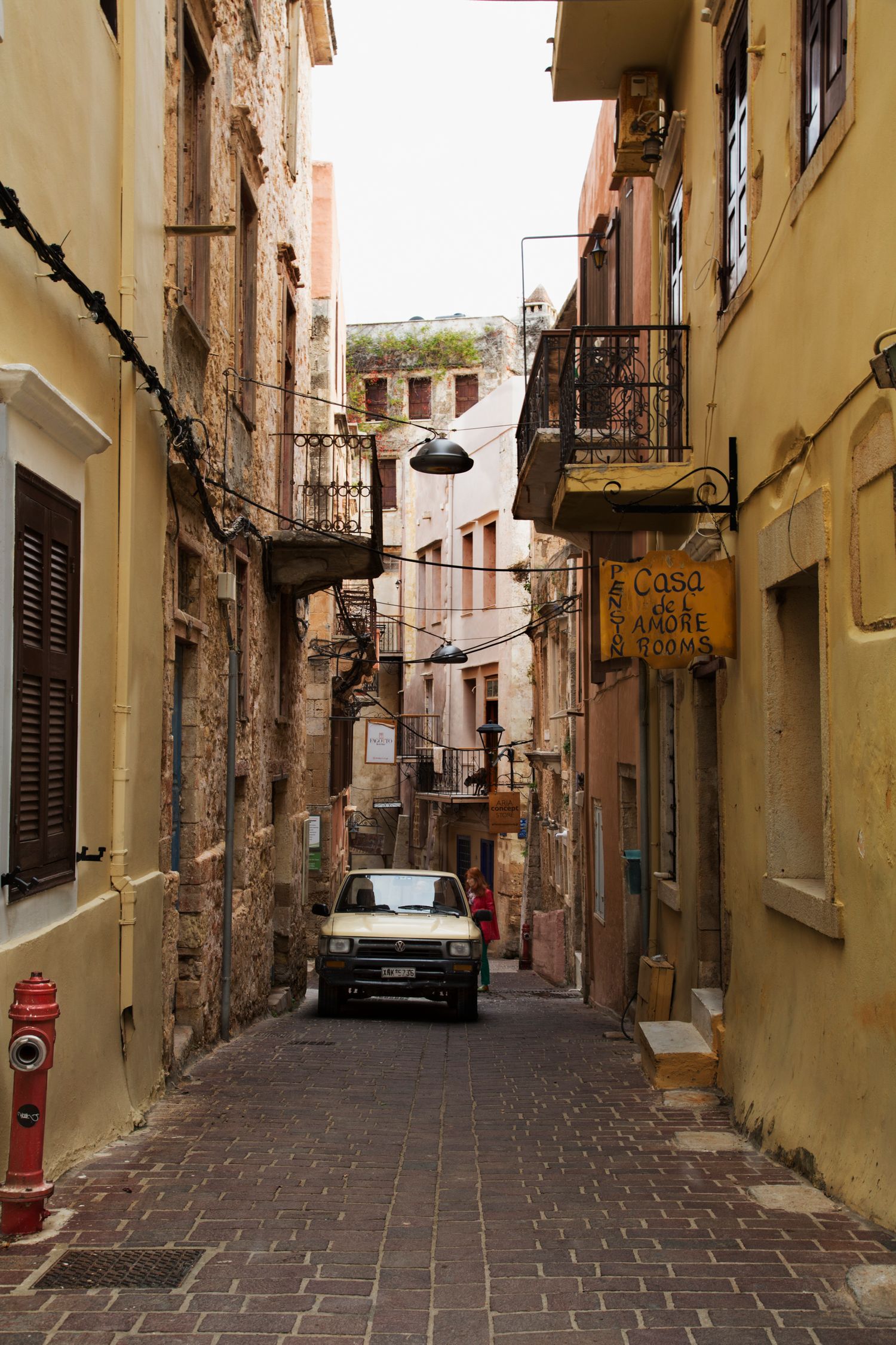 Narrow cobblestone alley between old buildings with vintage car parked in historic town.