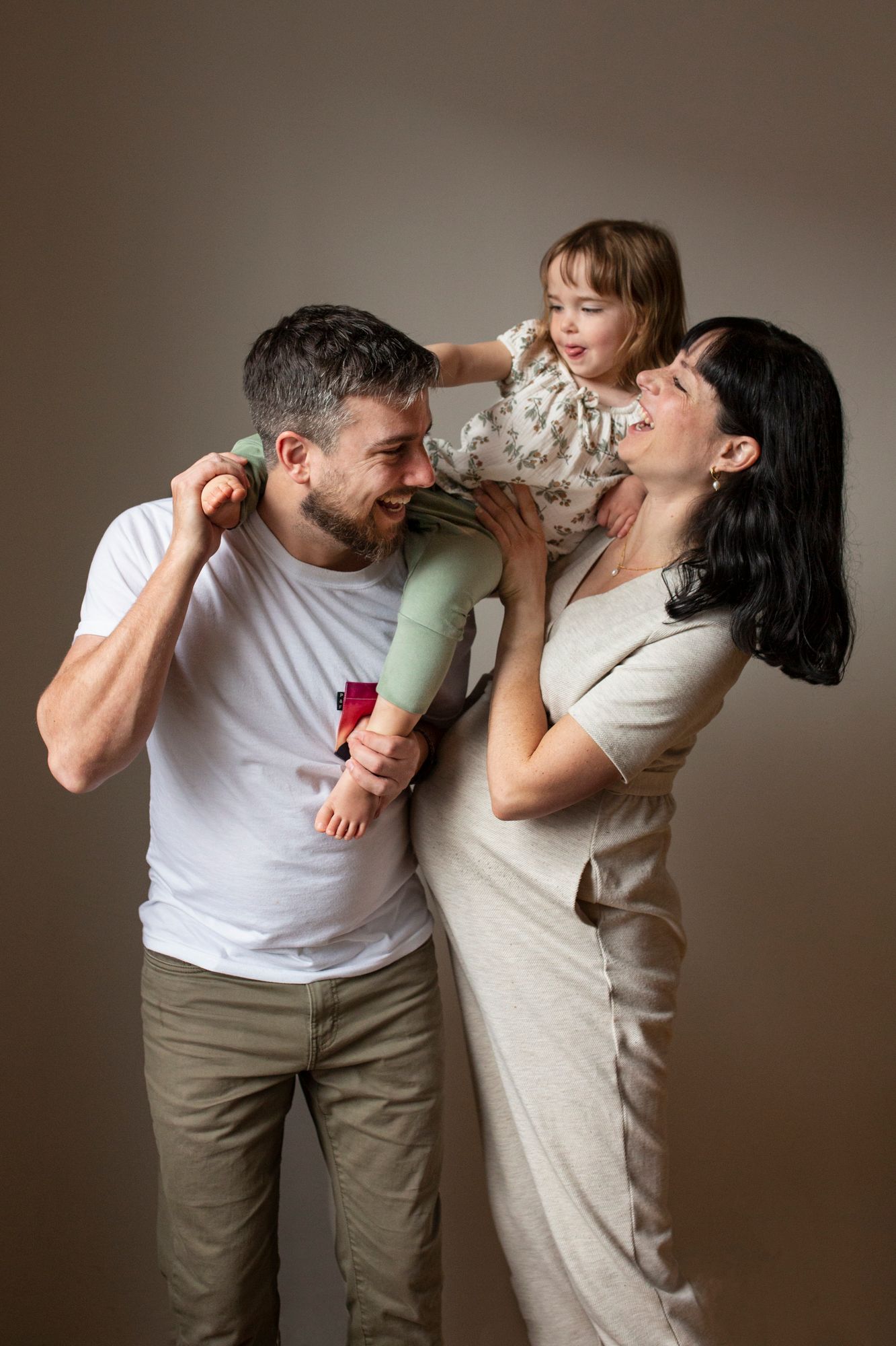 A couple playfully drinks from wine glasses in a series of romantic poses against a neutral background.