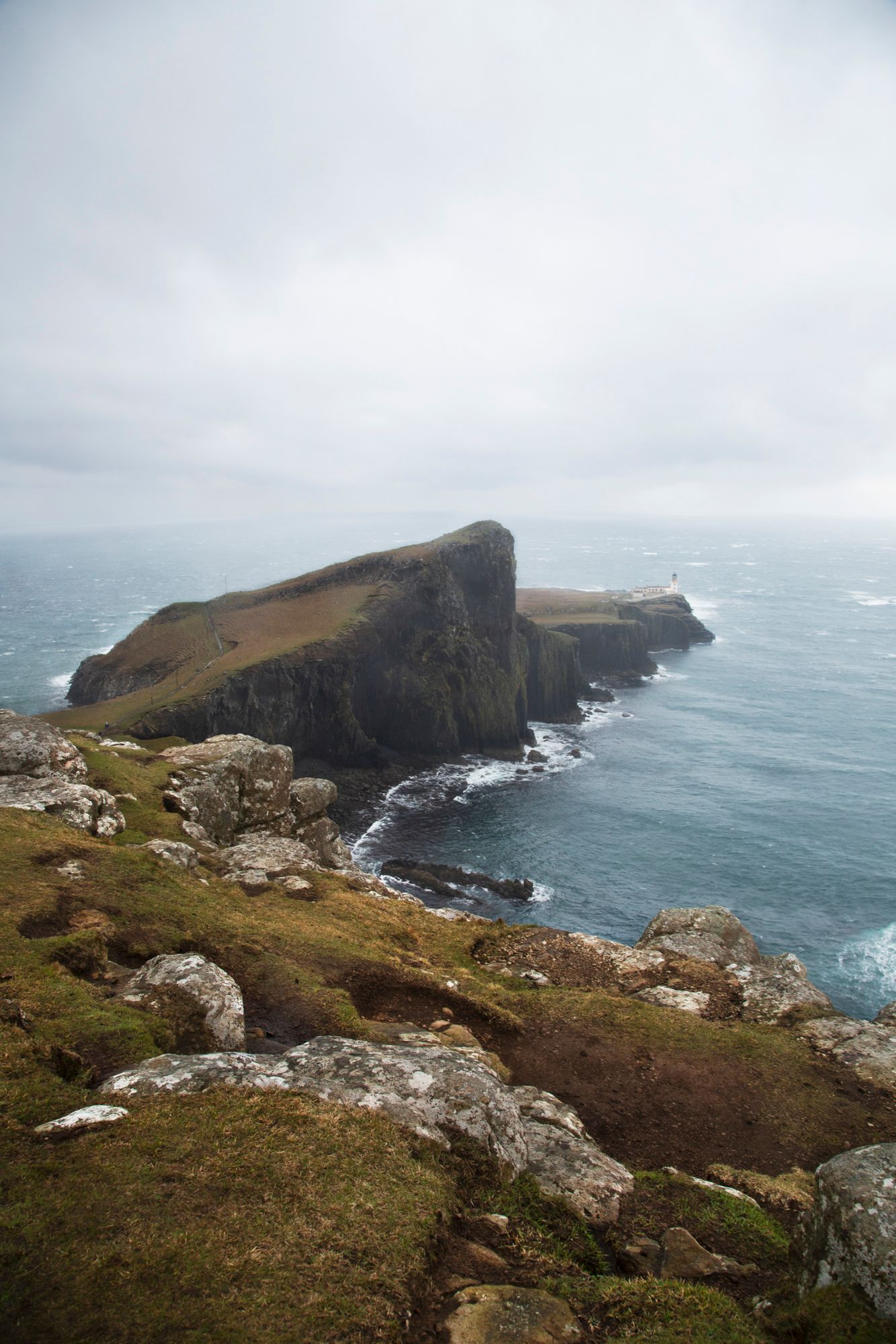 Dramatic coastal cliffs and rugged headlands along the misty coastline of Cornwall with crashing waves against rocky shores.