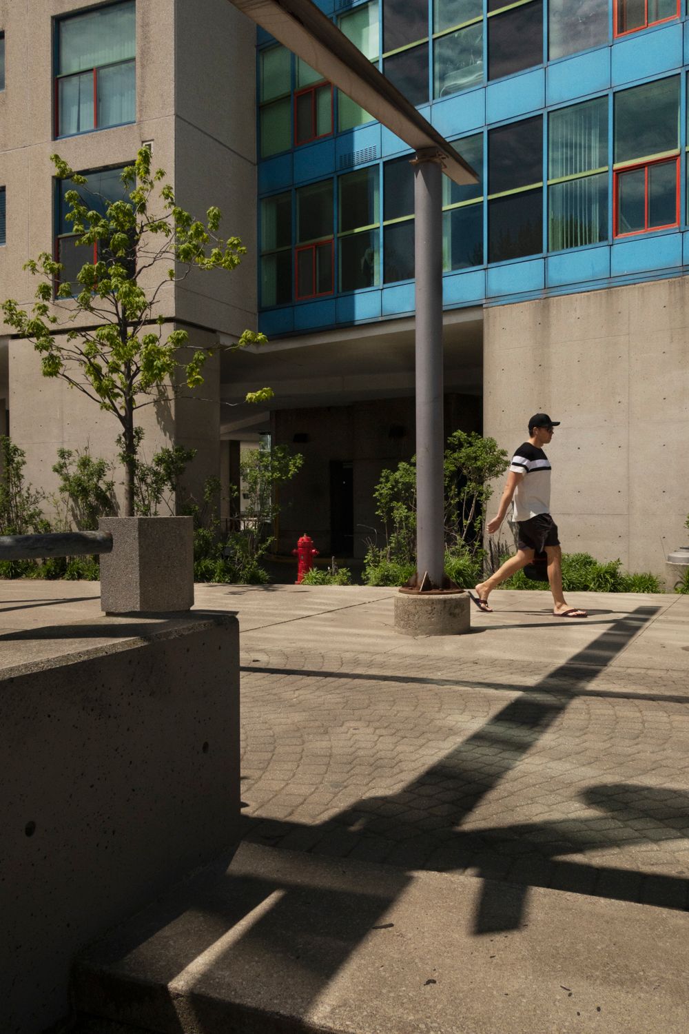 Modern apartment building courtyard with cast shadows on concrete pavement.