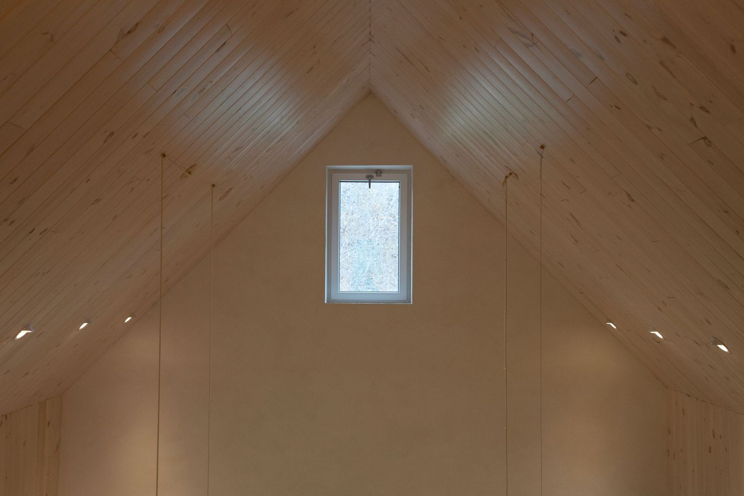Vaulted wooden ceiling with exposed beams and a small square skylight in natural pine finish.