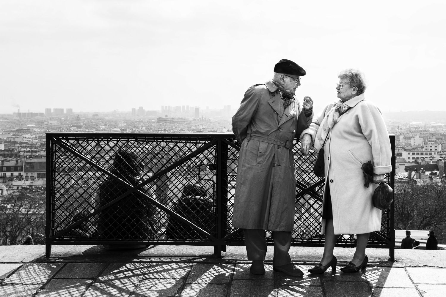 People enjoying a panoramic city view from an observation deck in black and white.