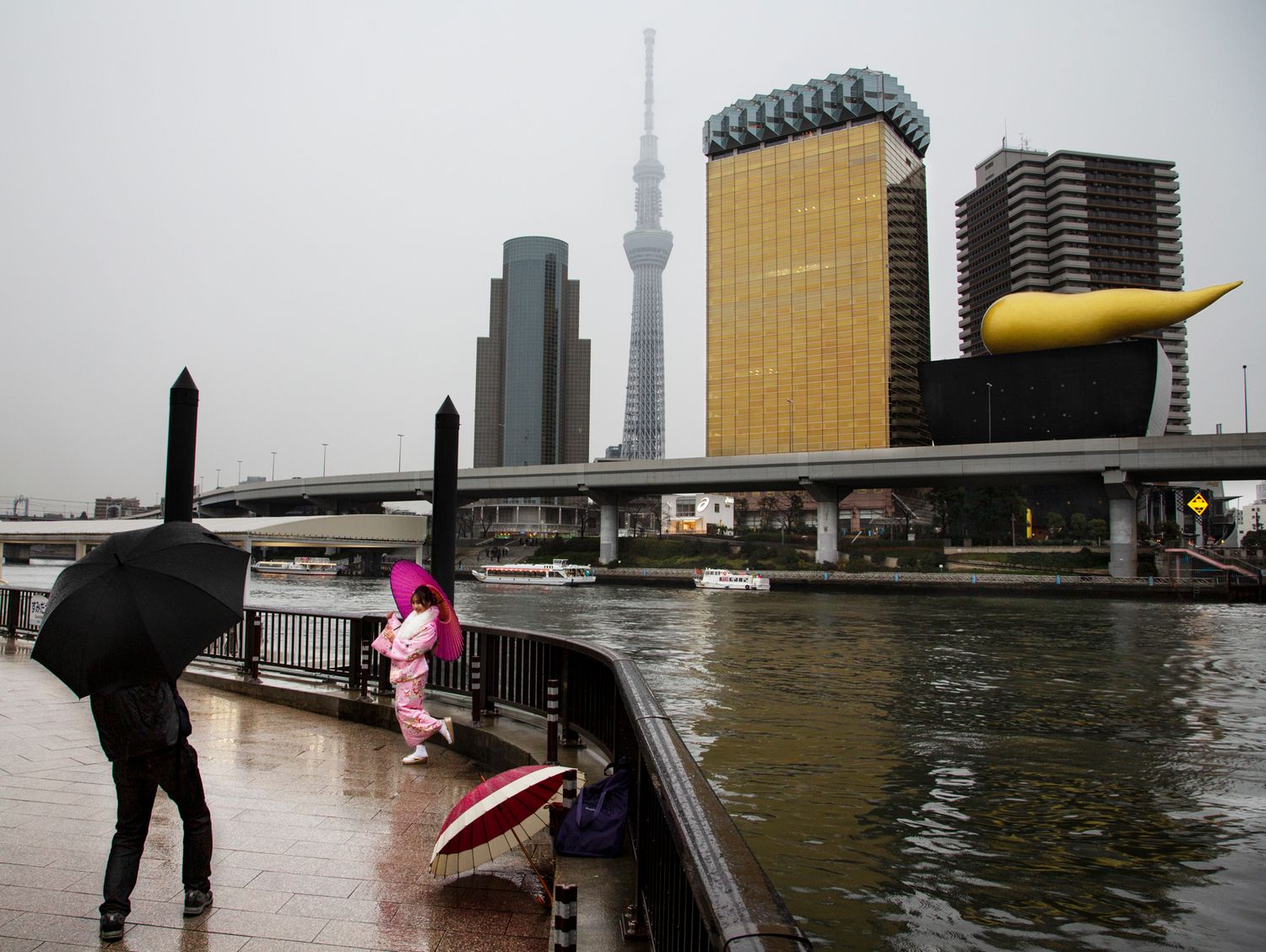 Modern city skyline reflected in water with silhouetted figures in the foreground.
