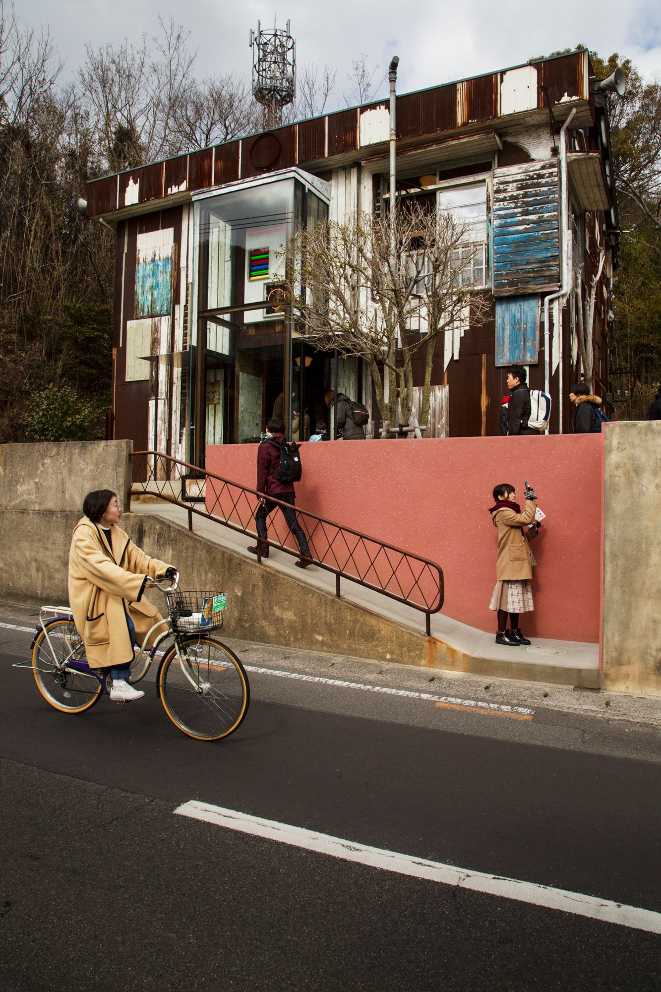 Residential street with red wall and bicycle path on a slope.