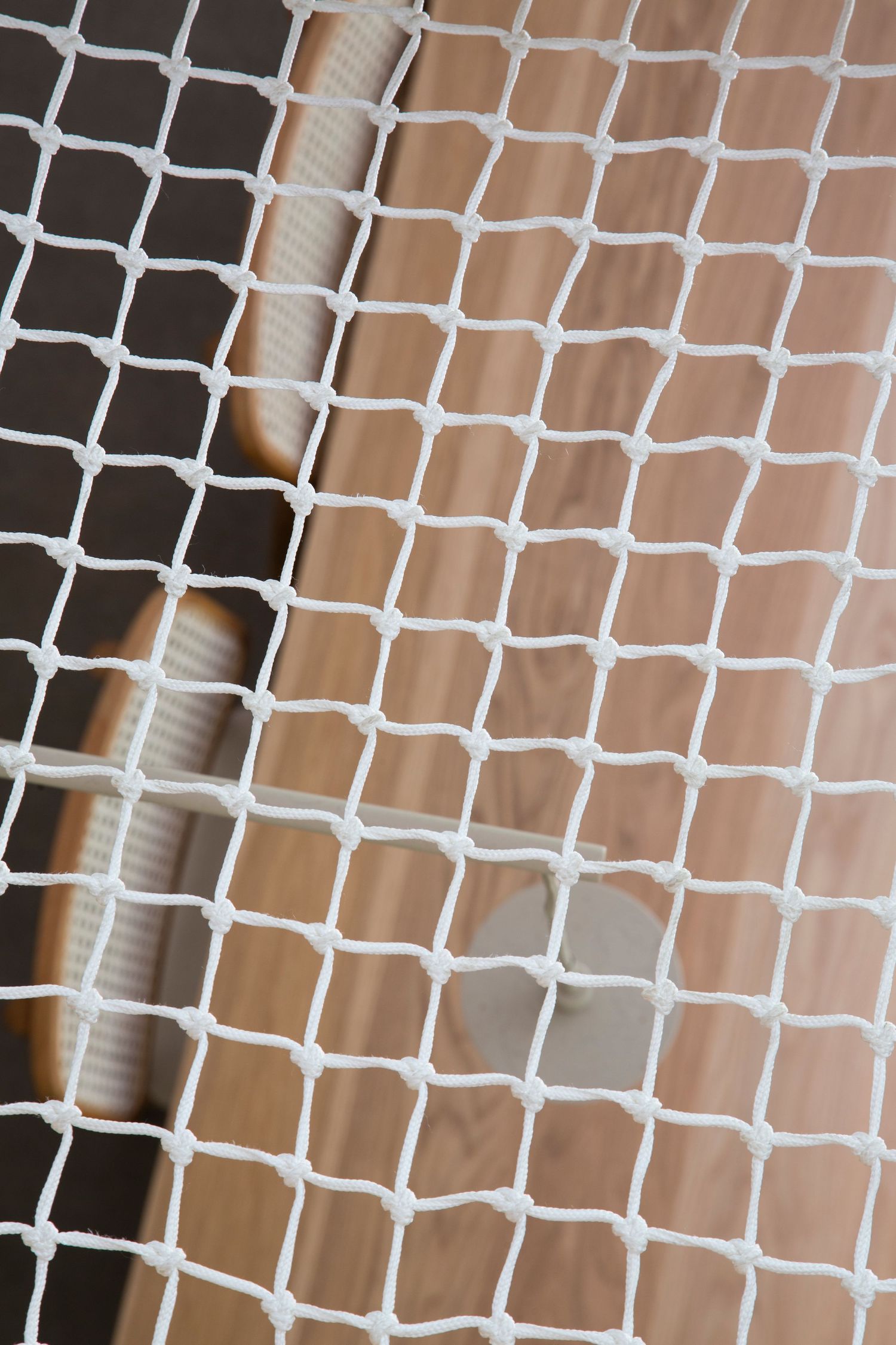 Abstract pattern of white mesh netting against a soft beige background.