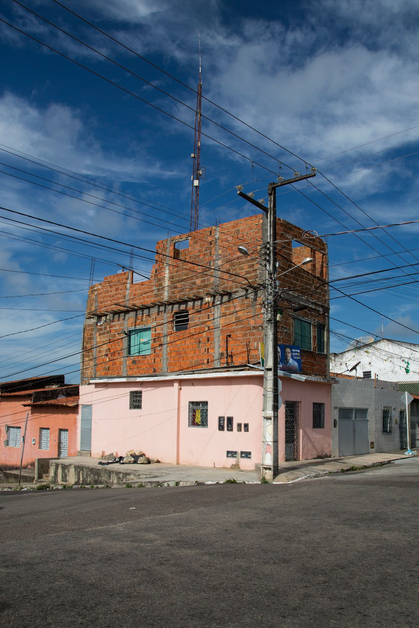 Row of simple brick and painted houses along a street with power lines overhead.